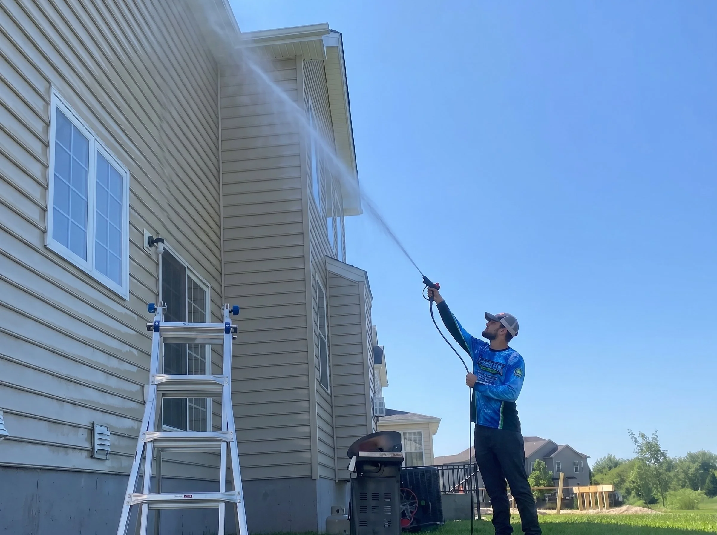 Hydrolux technician soft washing the exterior siding of a residential home
