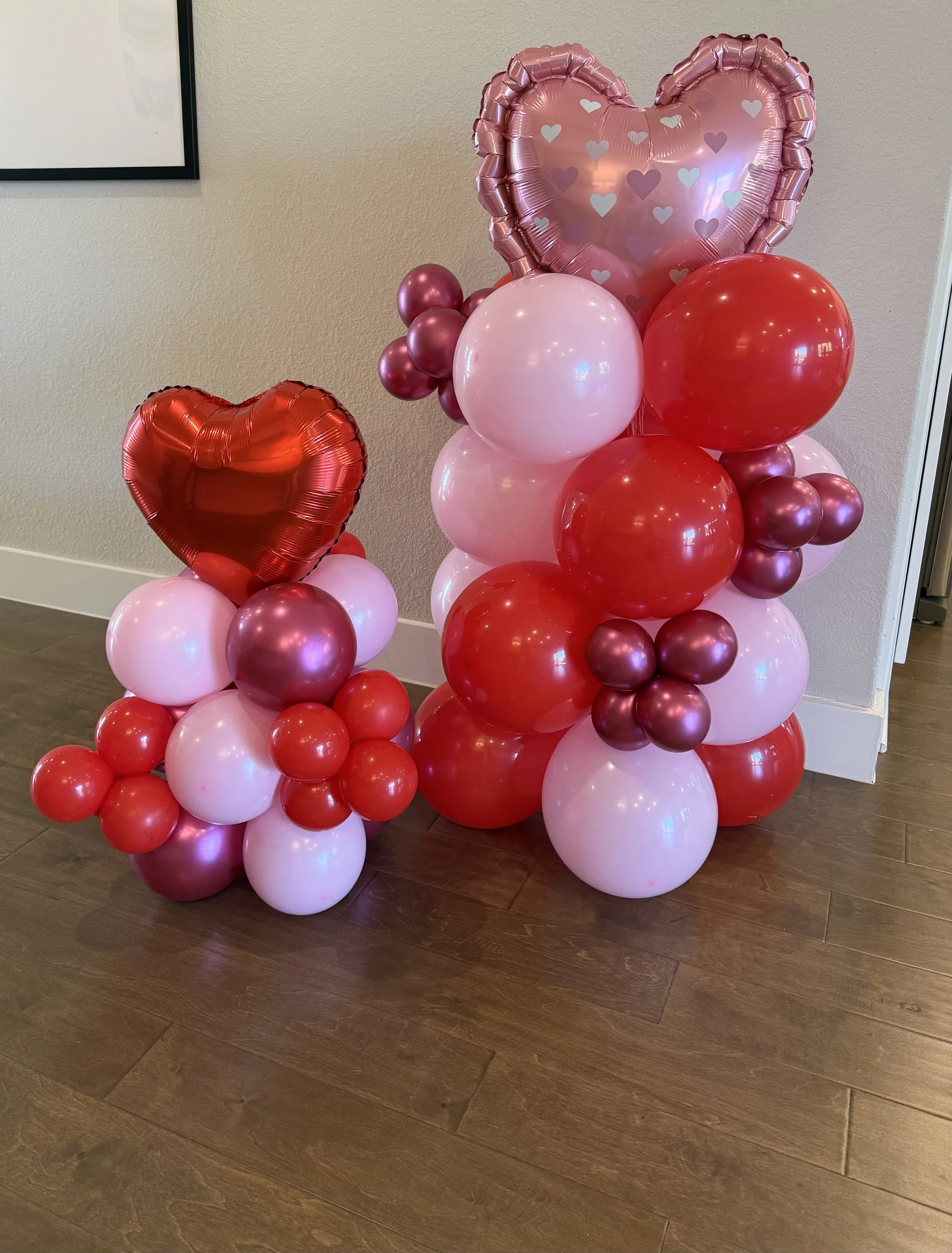 Valentine's day themed balloon columns in red, pink and white, with ornamental heart balloons, created by Dripping springs based ColorPop Balloon Studio.