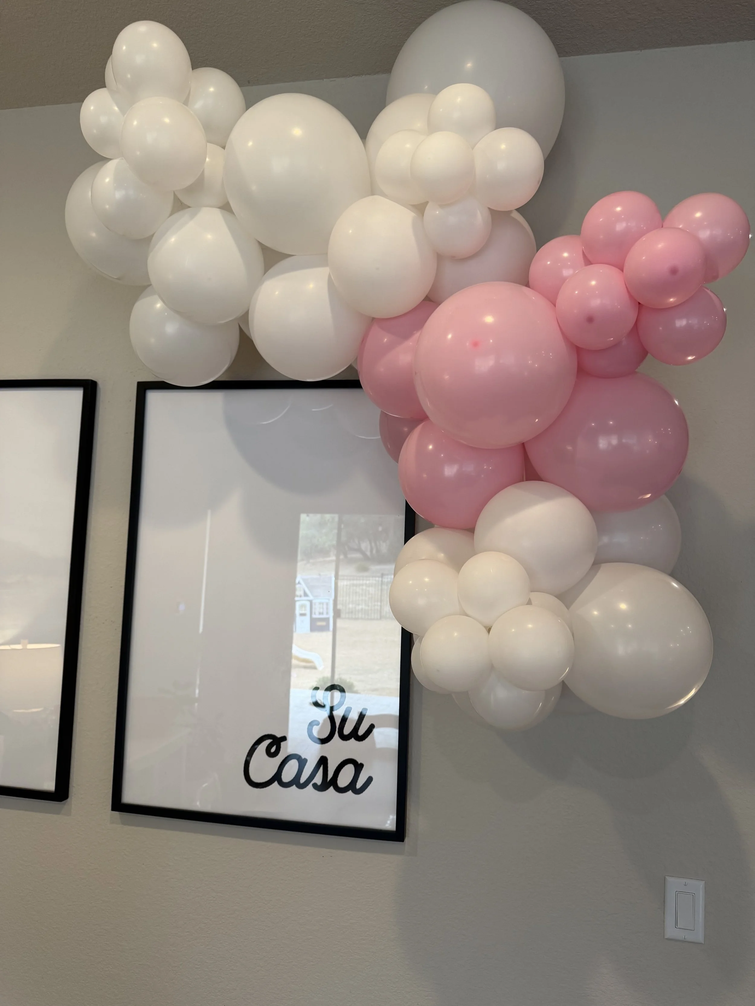 Pink and white balloon garland wrapped around wall art, perfect for baby showers or bridal showers, created by Dripping springs based ColorPop Balloon Studio.