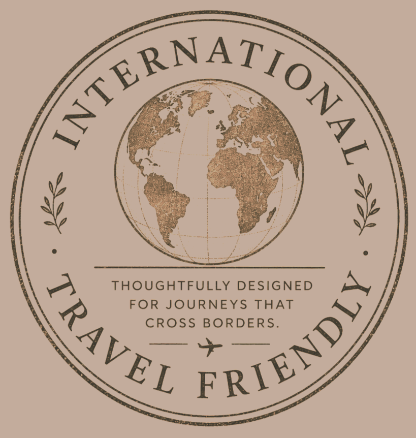 A circular logo featuring a textured globe of the world at the center, surrounded by the words 'International Travel Friendly' and decorative leaves. The logo includes the tagline 'Thoughtfully designed for journeys that cross borders' and a small airplane icon.