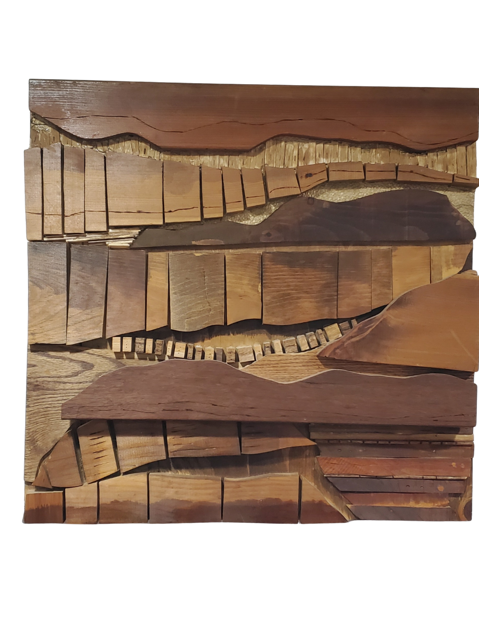 A square wooden art piece composed of various pieces of wood arranged to resemble a mountainous landscape.