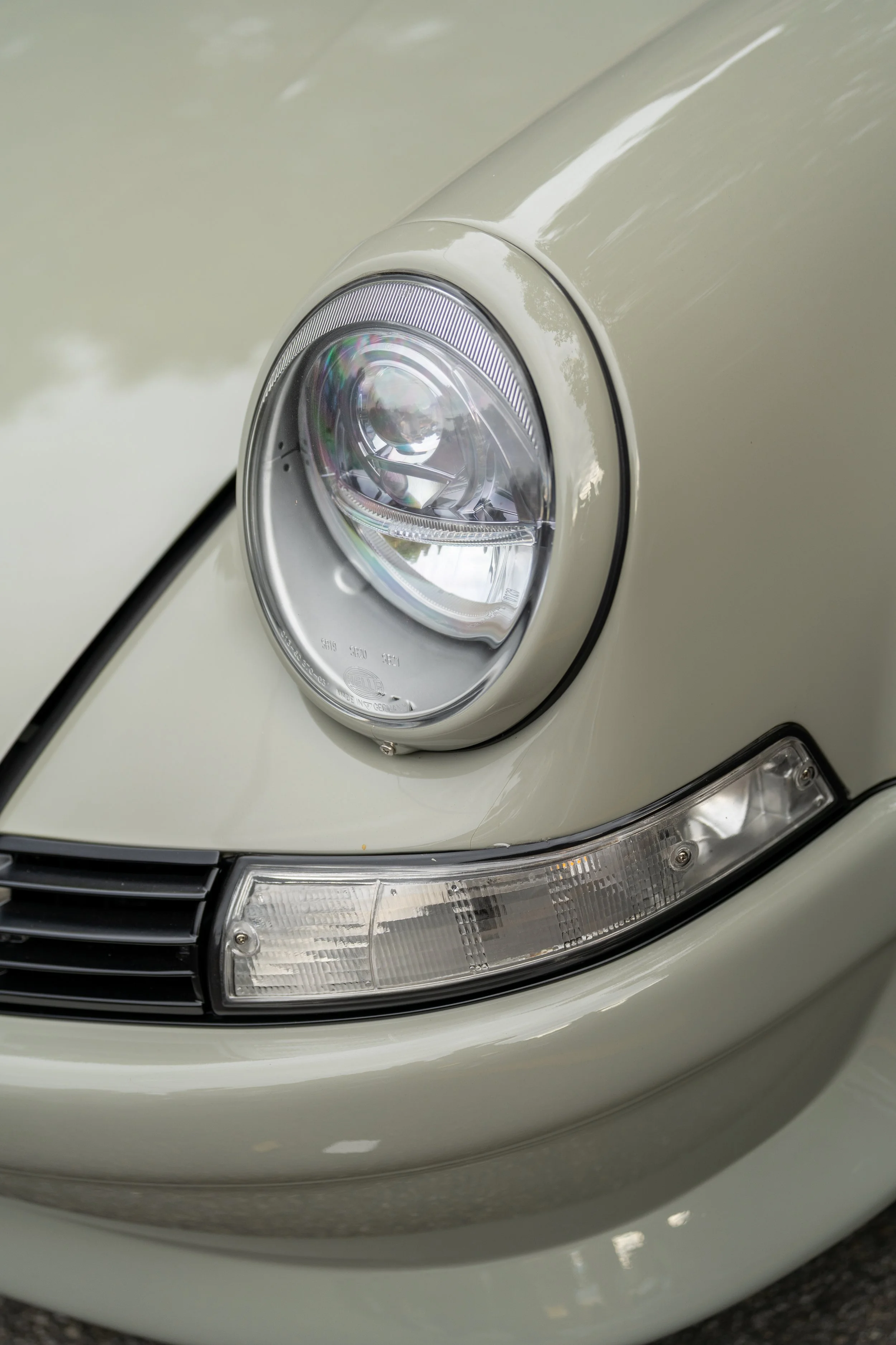 Close-up of a beige car's front headlight and bumper. vintage porsche 911 930