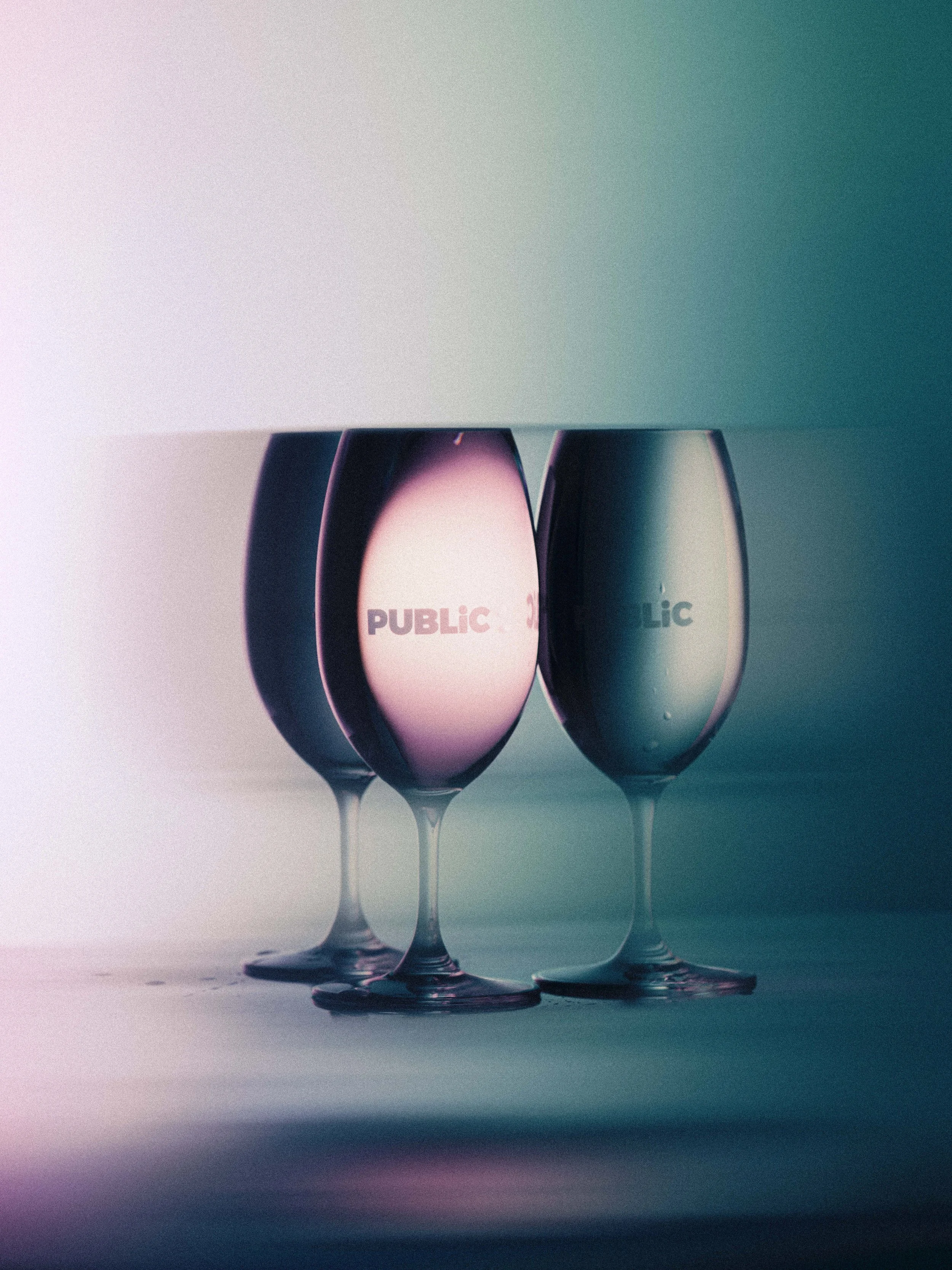 Three wine glasses with word stickers, one says 'PUBLIC' and the others are partially obscured. public manuka wine glasses