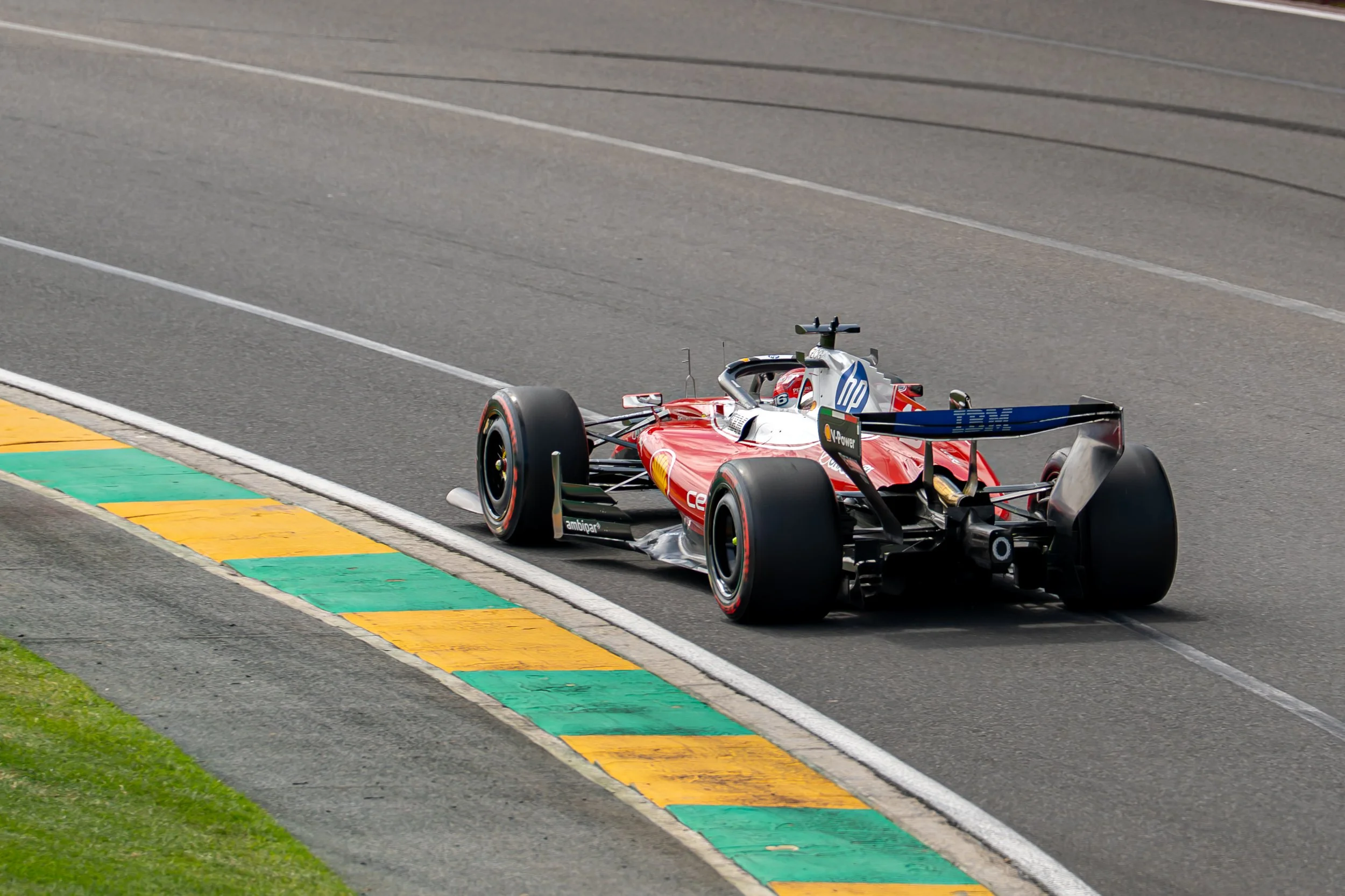 A red Formula 1 race car on a race track with green, yellow, and black curb markings at the edge of the track. charles leclerc ferrari f1 formula 1 australian grand prix 2026  