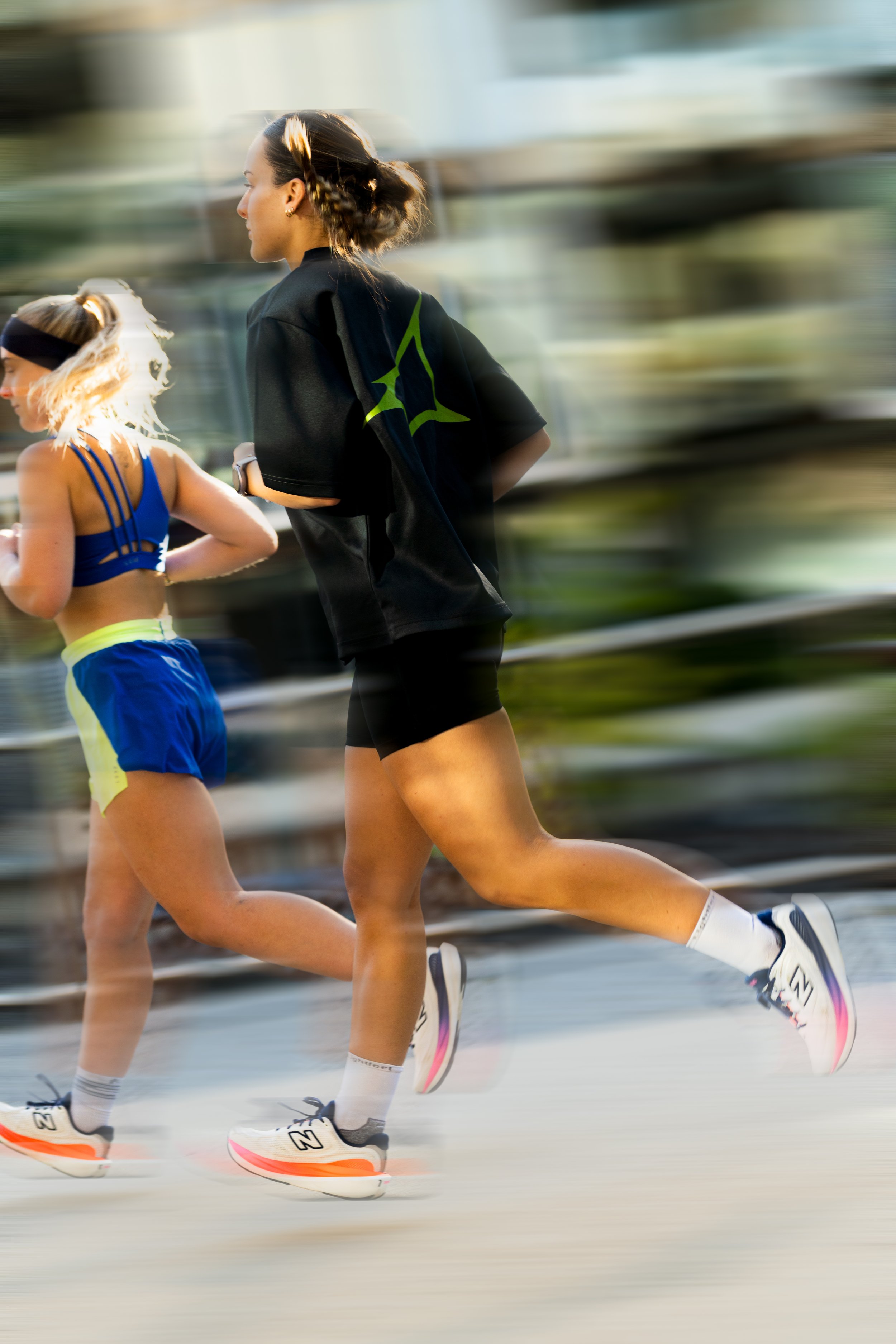 Two women running outdoors, wearing athletic clothing and sneakers, with motion blur indicating speed. run club Canberra PAX sports photography