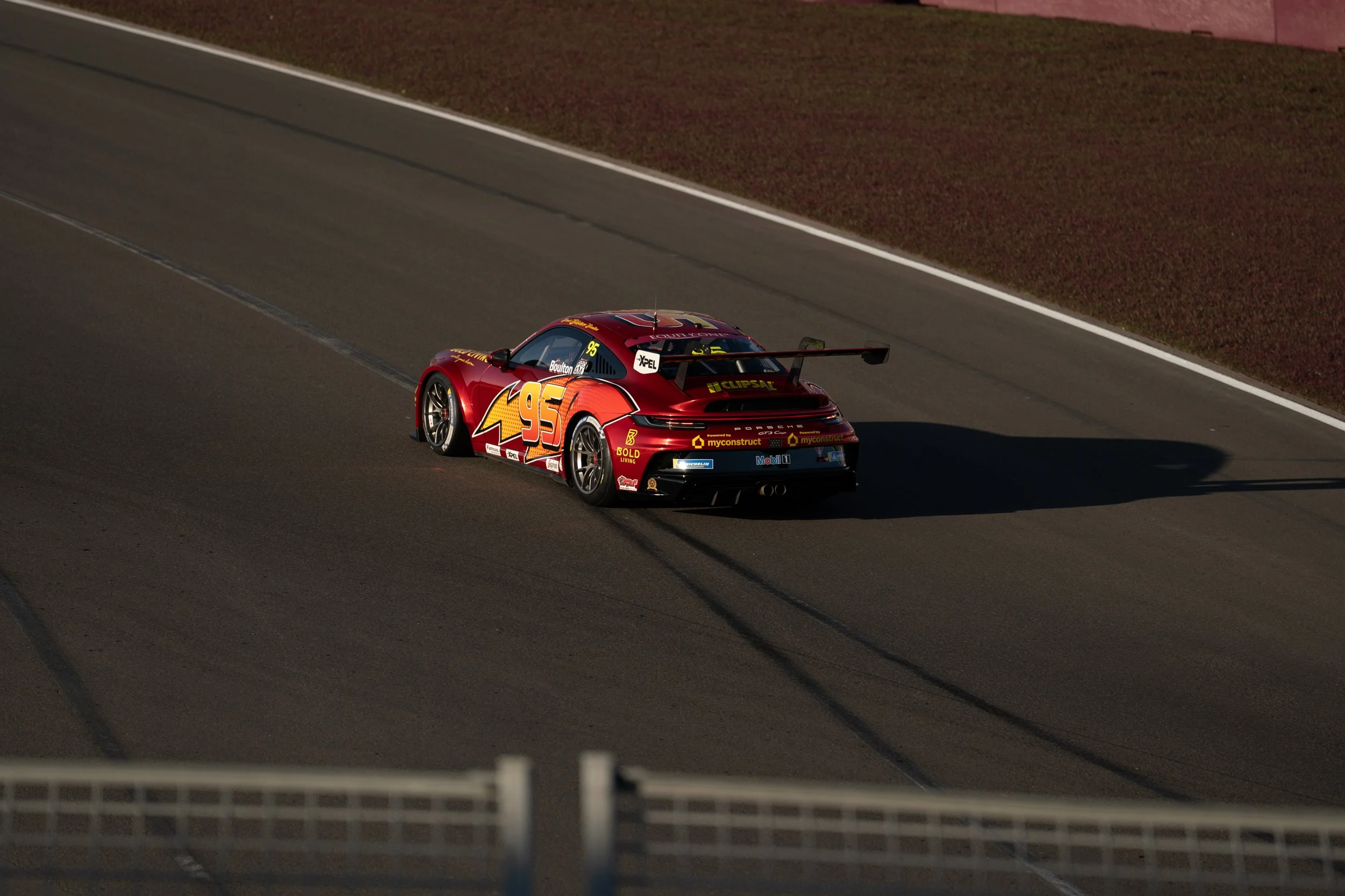 A red race car with the number 95 on the side, near the end of a race on a track. lightening mcqueen porsche 911 gt3 Carrera Cup australian grand prix 2026