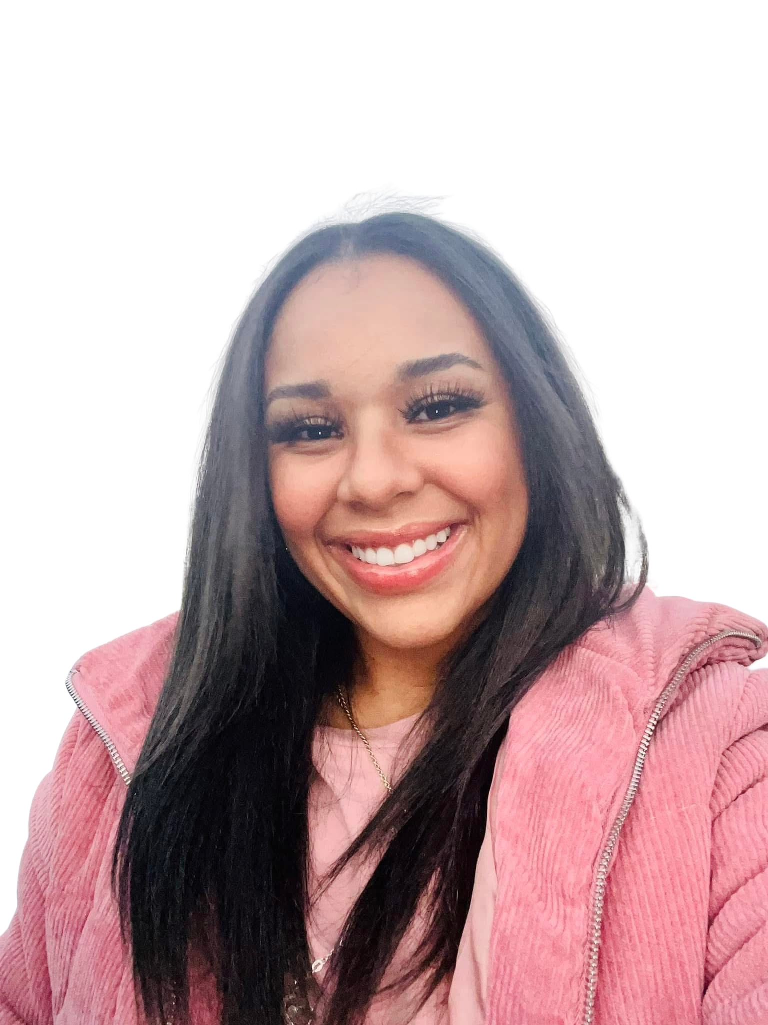 Close-up of a smiling woman with long dark hair, wearing a pink jacket and a necklace.