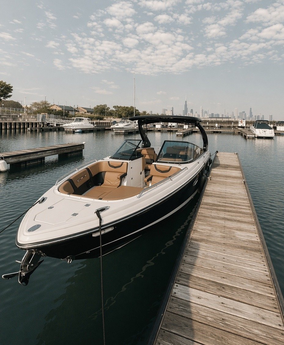 A boat docked at a marina with multiple boats and a city skyline in the background, under a partly cloudy sky.