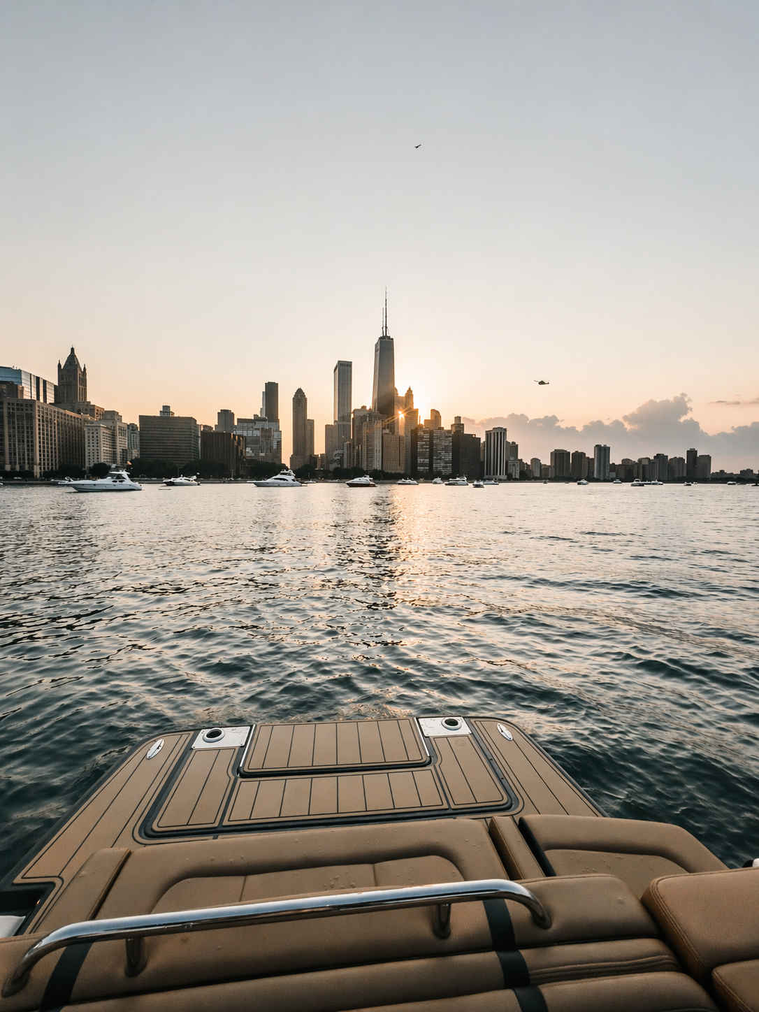 View of a city skyline at sunset seen from a boat on the water, with multiple yachts and a dock in the foreground.