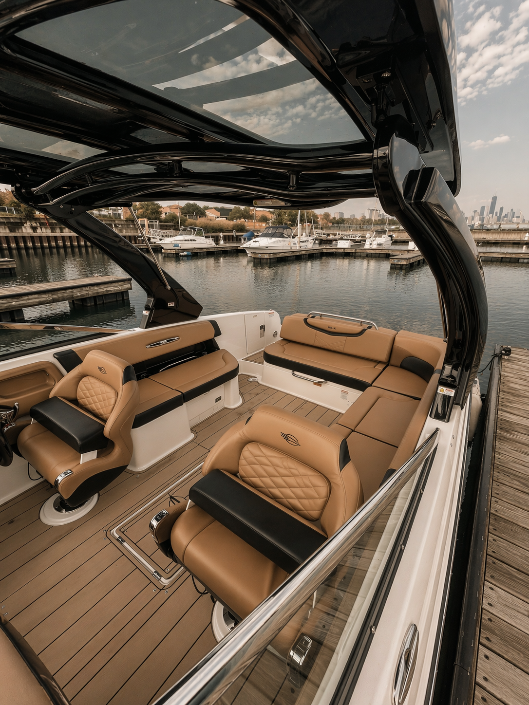 Interior of a luxury boat with tan leather seats and a wooden floor, docked at a marina with other boats and a city skyline in the background.