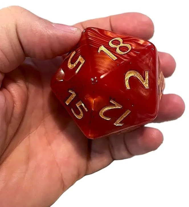 A hand holding a red and orange marbled twenty-sided die with silver numbers.