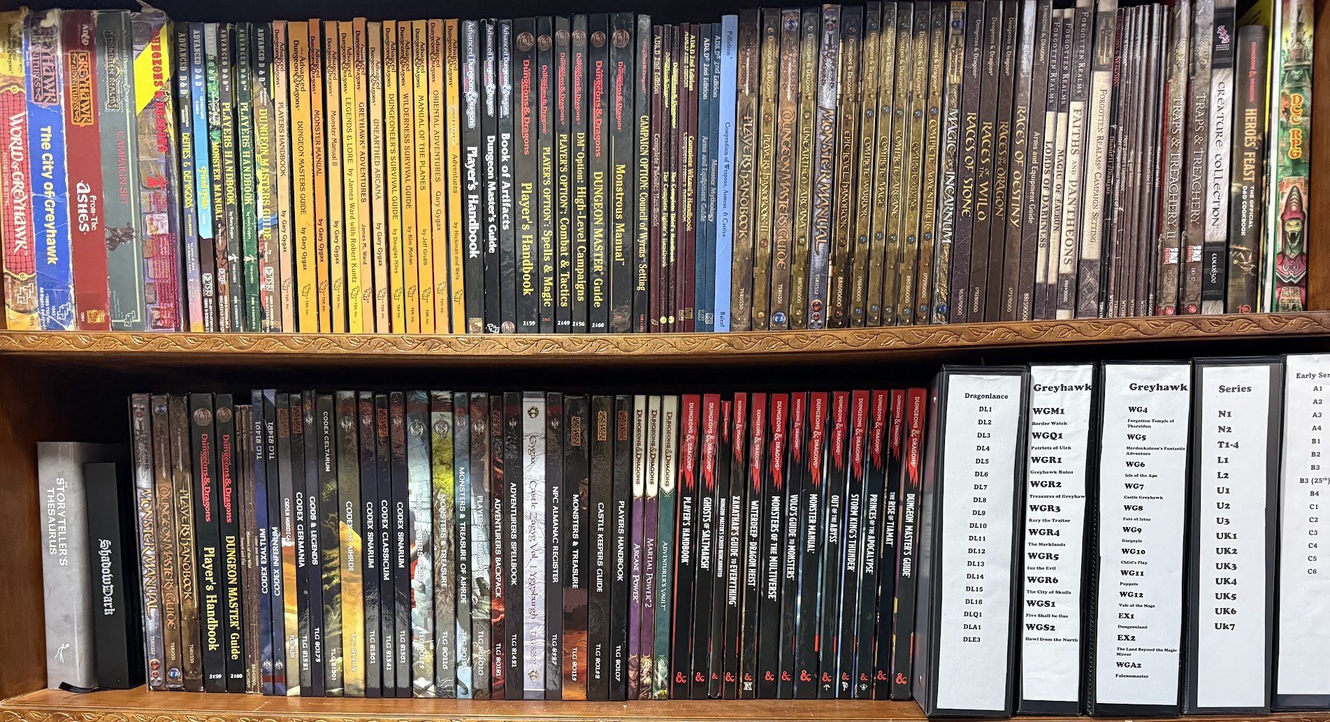 Bookcase filled with tabletop role-playing game books, primarily Dungeons & Dragons, including rulebooks, guides, adventure modules, and expansion sets arranged on two shelves.