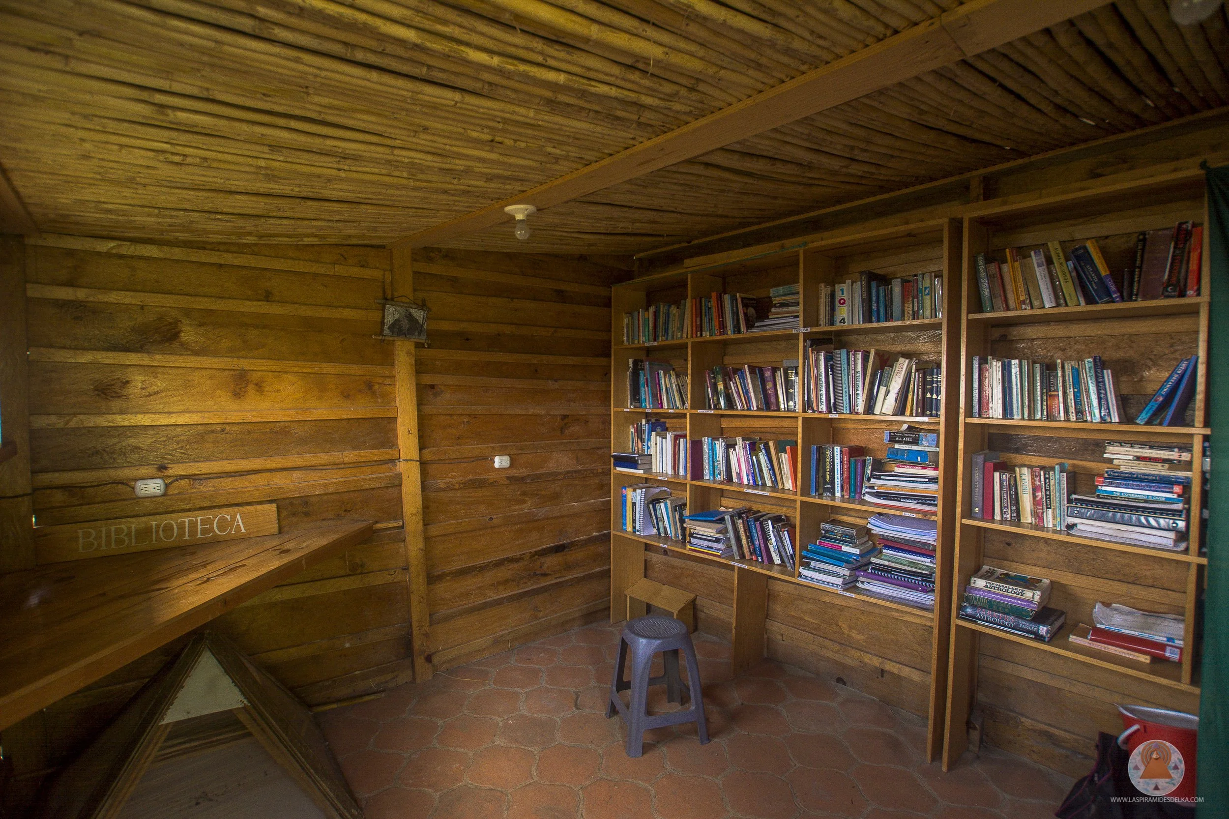 Una biblioteca de madera con estanterías llenas de libros y un cartel que dice 'Biblioteca' en la esquina.