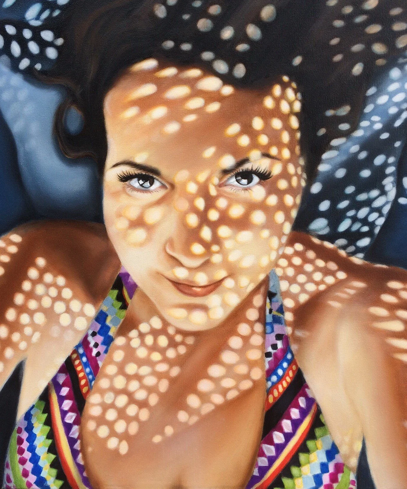 A woman lying on her back, taking a selfie with a pattern of circular light reflections on her face and body. She has dark hair and is wearing a colorful, patterned top.
