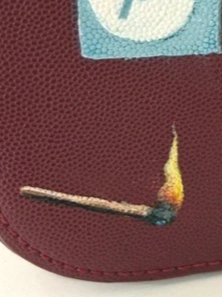 Close-up of a red textured surface with a small, burnt matchstick resting on it.