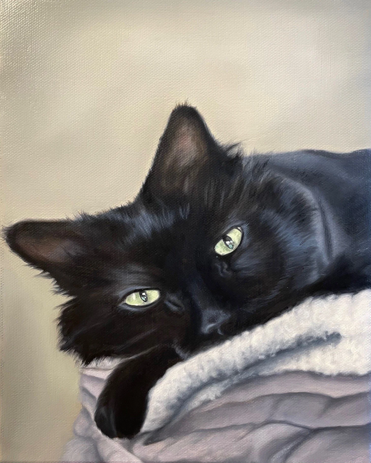 A black and white cat with green eyes lying on a soft surface, with part of its face and body visible.