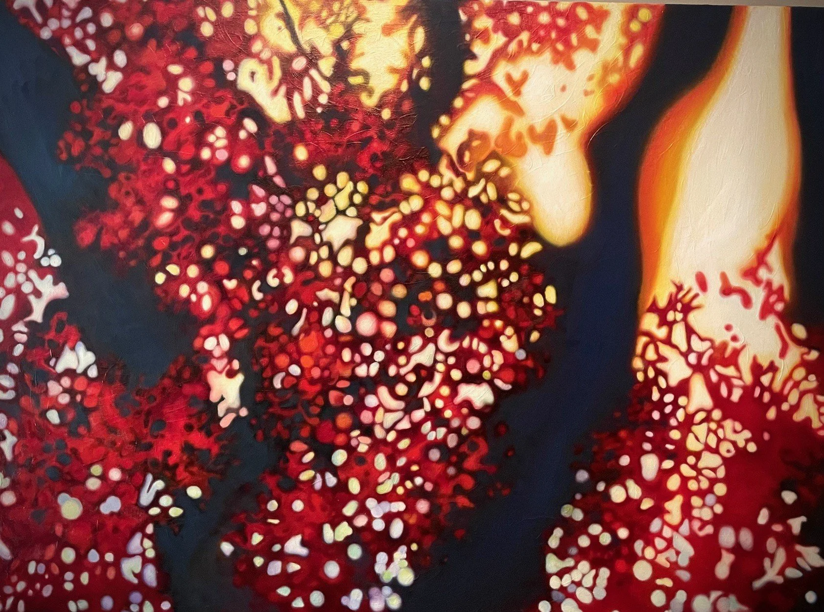 Abstract painting with vibrant reds, oranges, and black, featuring swirling patterns and dot-like shapes.