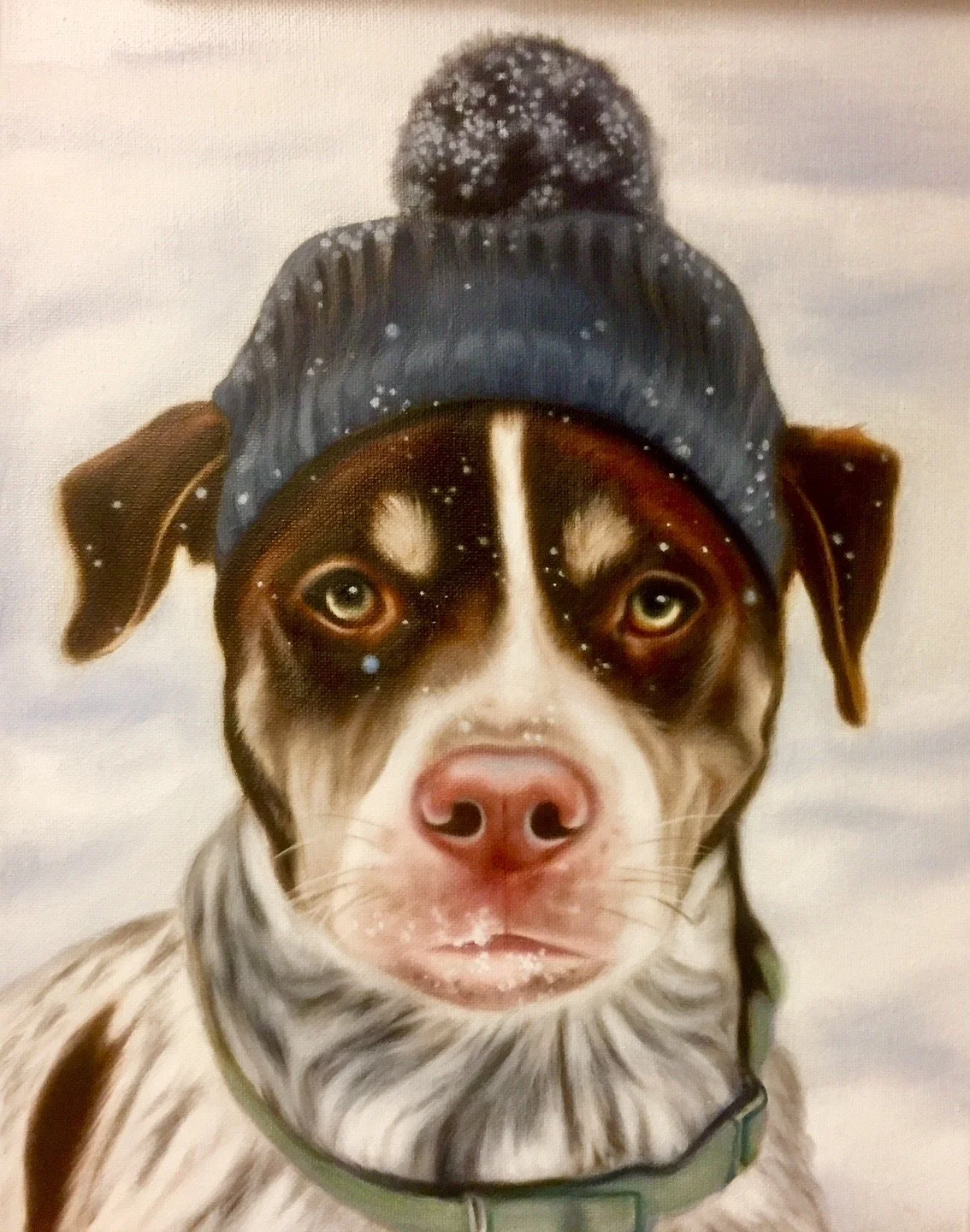 A dog wearing a blue knit hat with a pom-pom on top, in a snowy environment