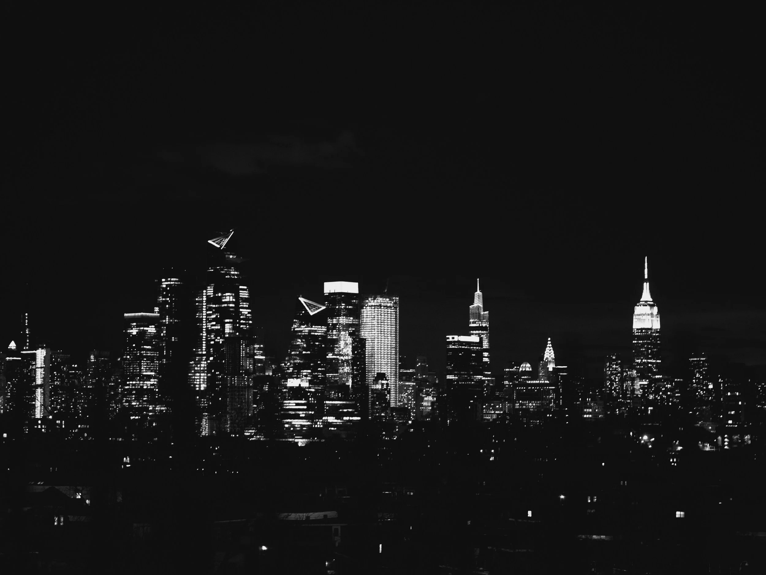 Nighttime city skyline with illuminated skyscrapers and a dark sky.