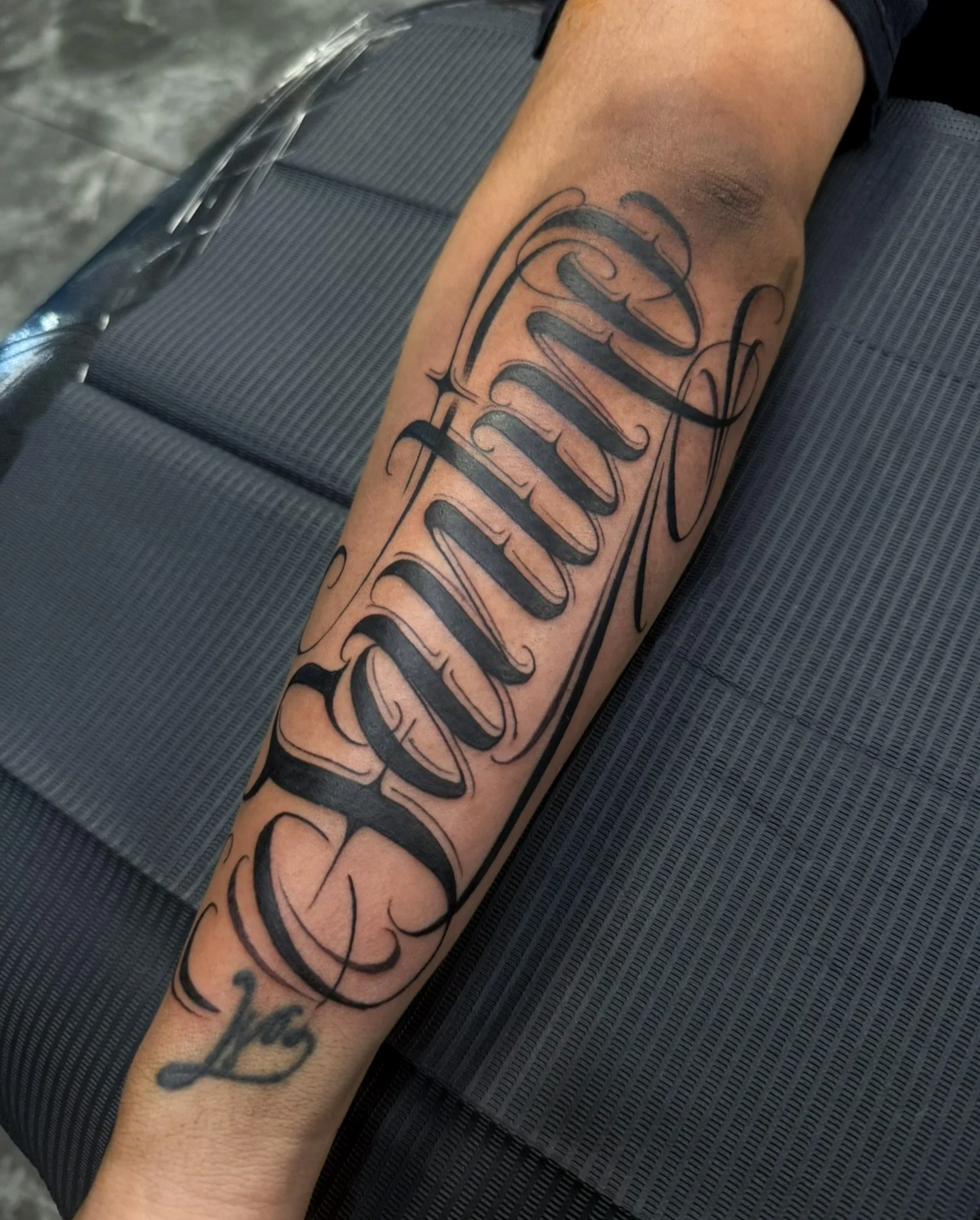 Tattoo on person's forearm with the word 'Fearless' in large, decorative, cursive black ink.
