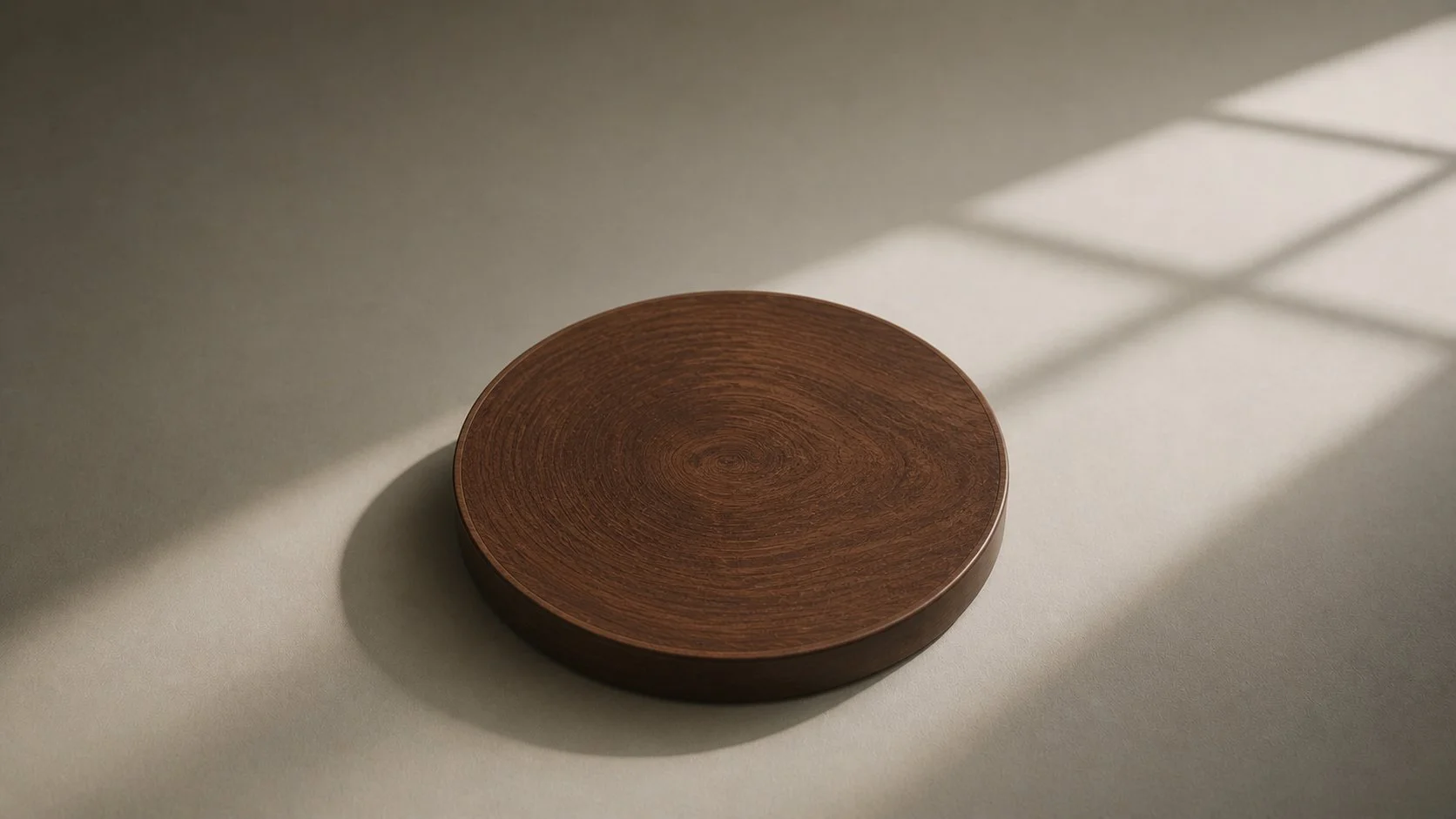 A round wooden tray on a light-colored surface with a shadow cast by a window grid.