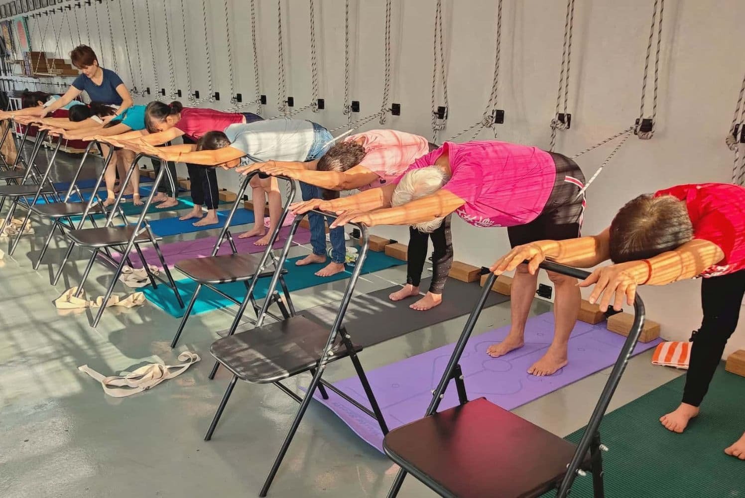 Seniors practicing Iyengar yoga with chair props at Simple Life Yoga studio in KL