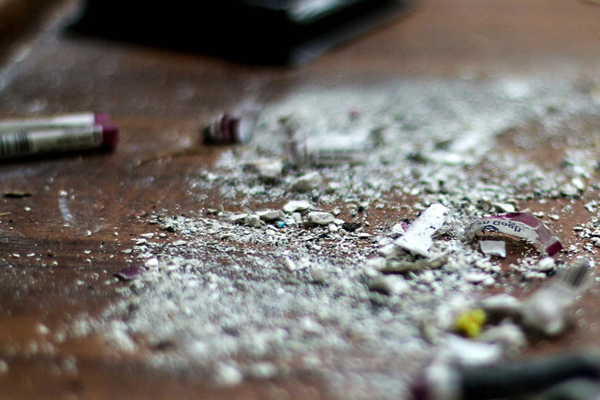 Close-up image of a dirty wooden surface scattered with crushed paper, cigarette butts, and small trash debris.