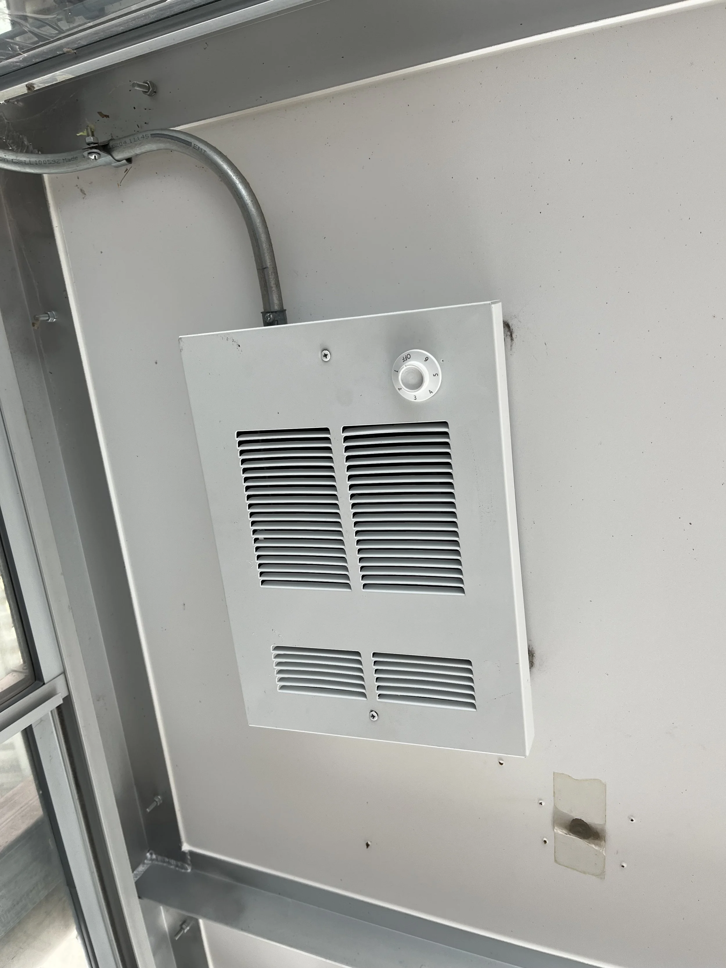 Ceiling vent and temperature control knob inside a metal enclosure, possibly part of an HVAC system or electrical panel.