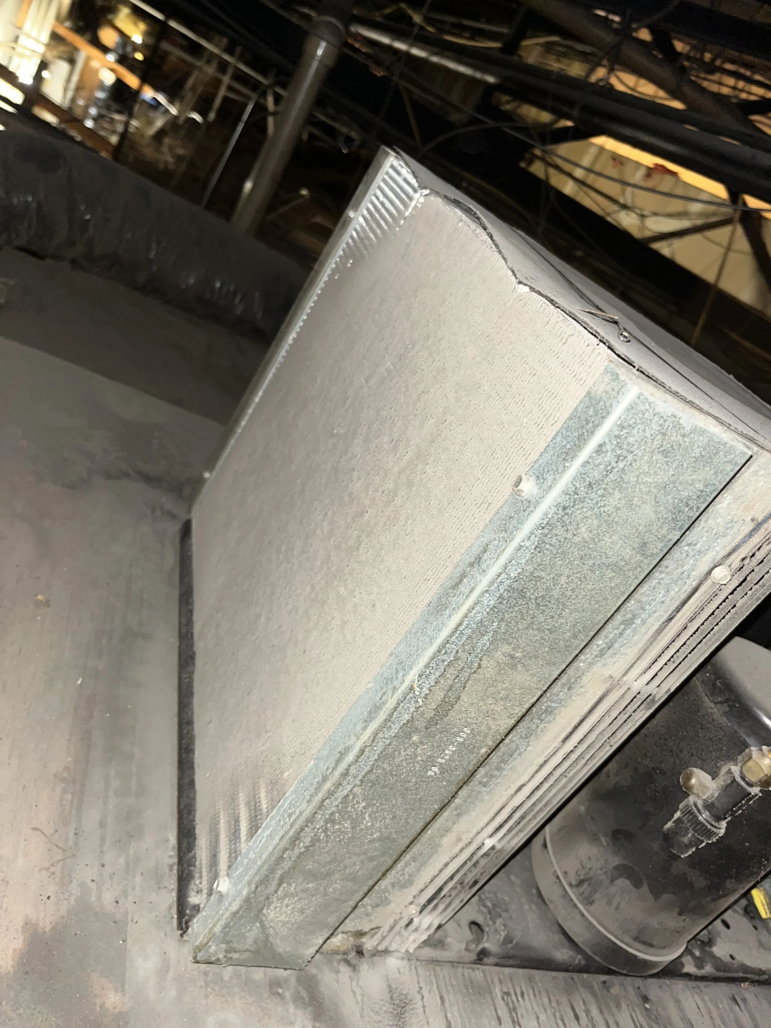 Industrial HVAC unit installed in a building with a visible duct system and surrounding construction materials.