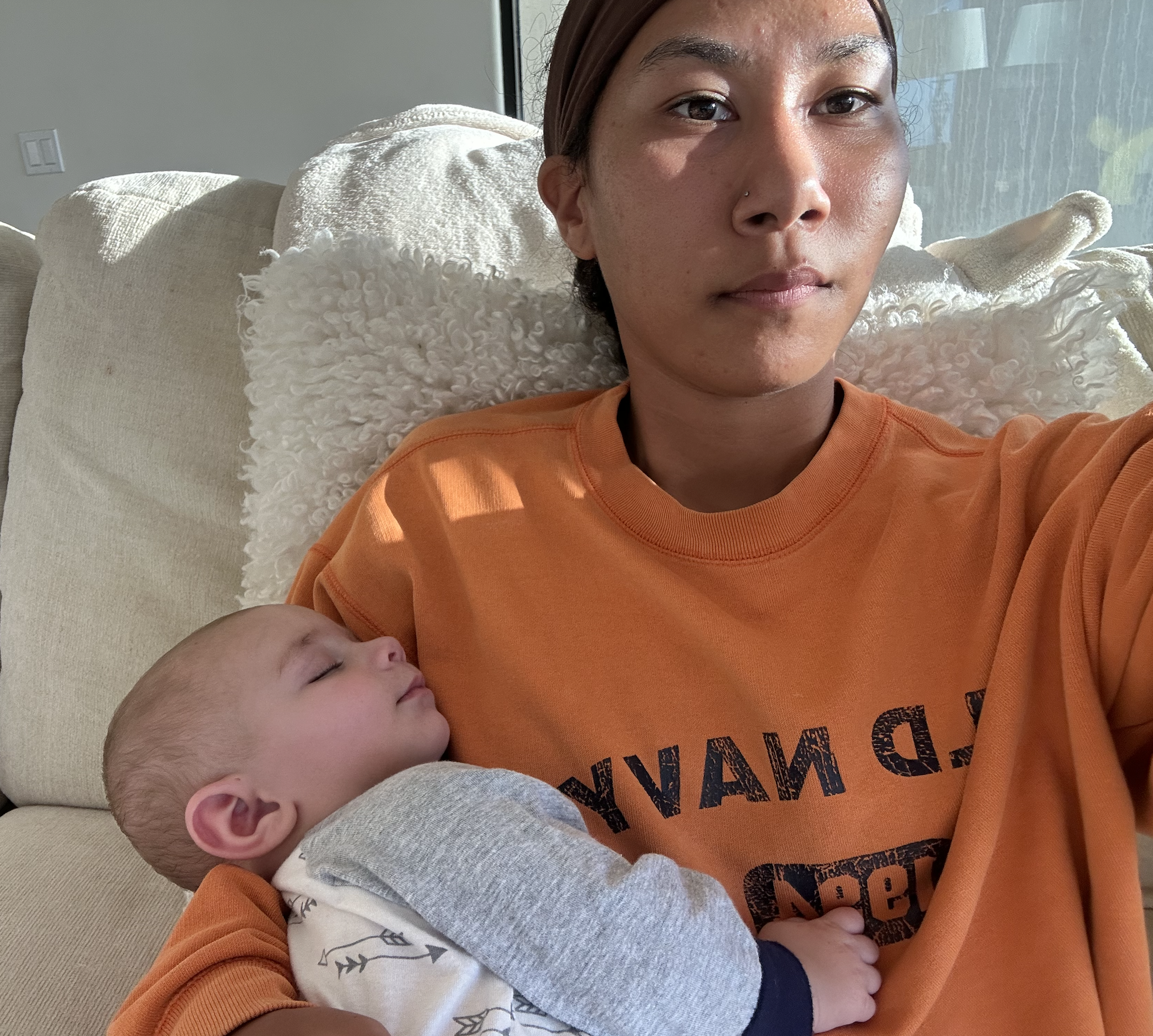 Girl in orange shirt holding sleeping baby