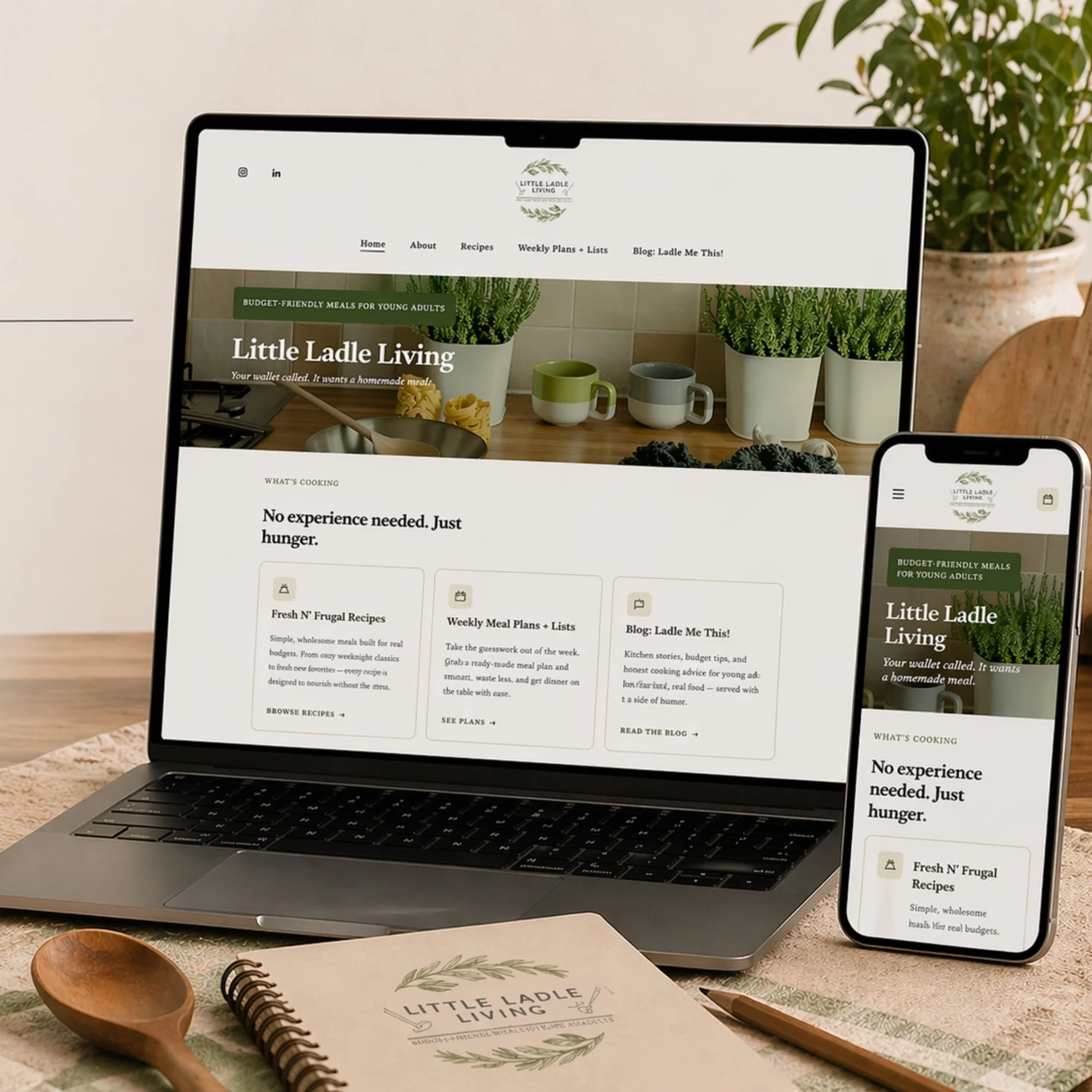 A laptop and phone displaying a website called Little Ladle Living, featuring recipes and meal plans, sitting on a table with a notebook, wooden spoon, and a plant in the background.