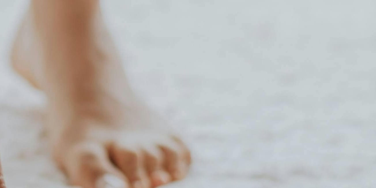 Close-up of a person's foot with toes, standing on a white surface.