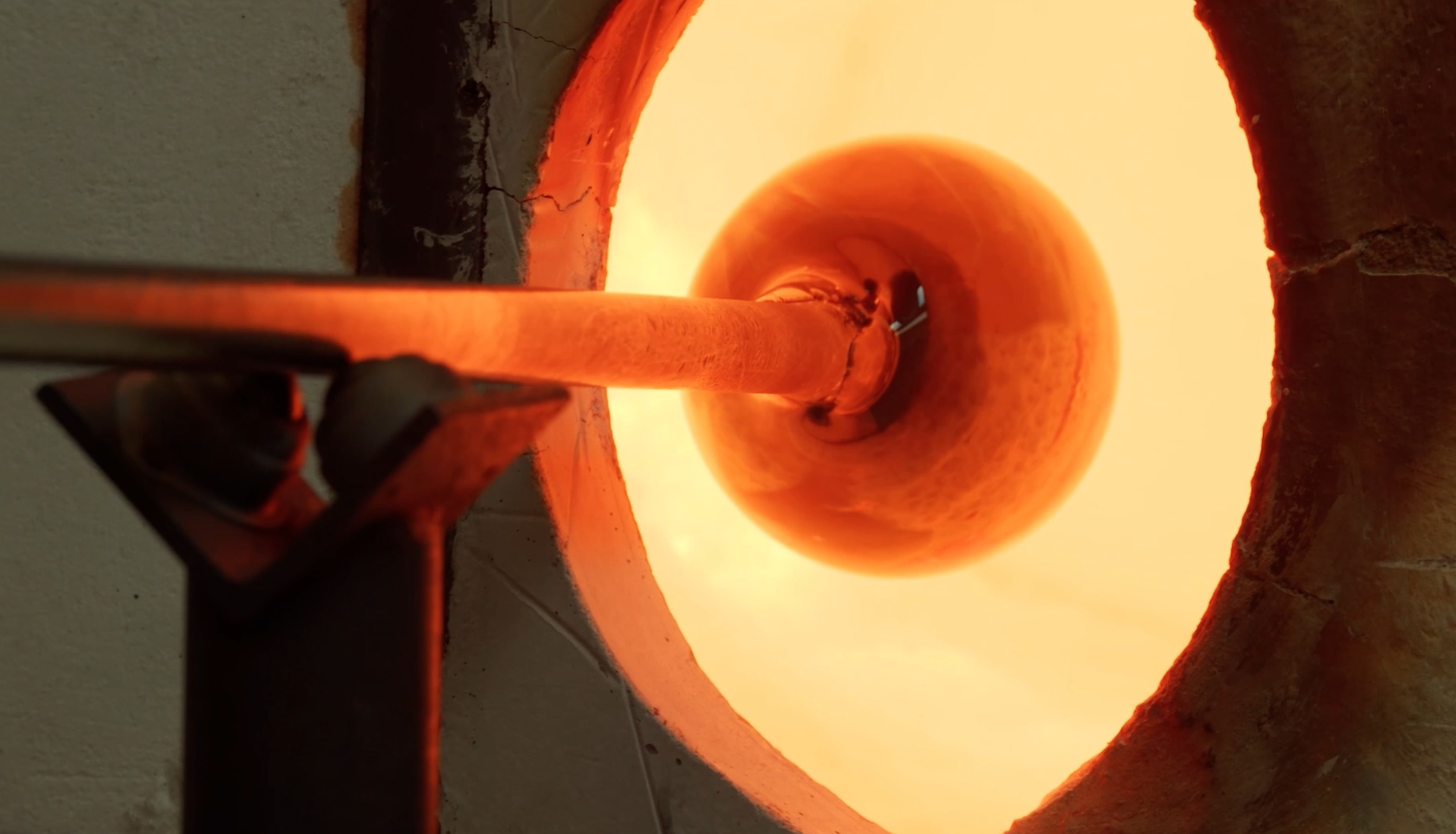 A close-up view of a furnace with bright orange flames, steel pipe, and brickwork.
