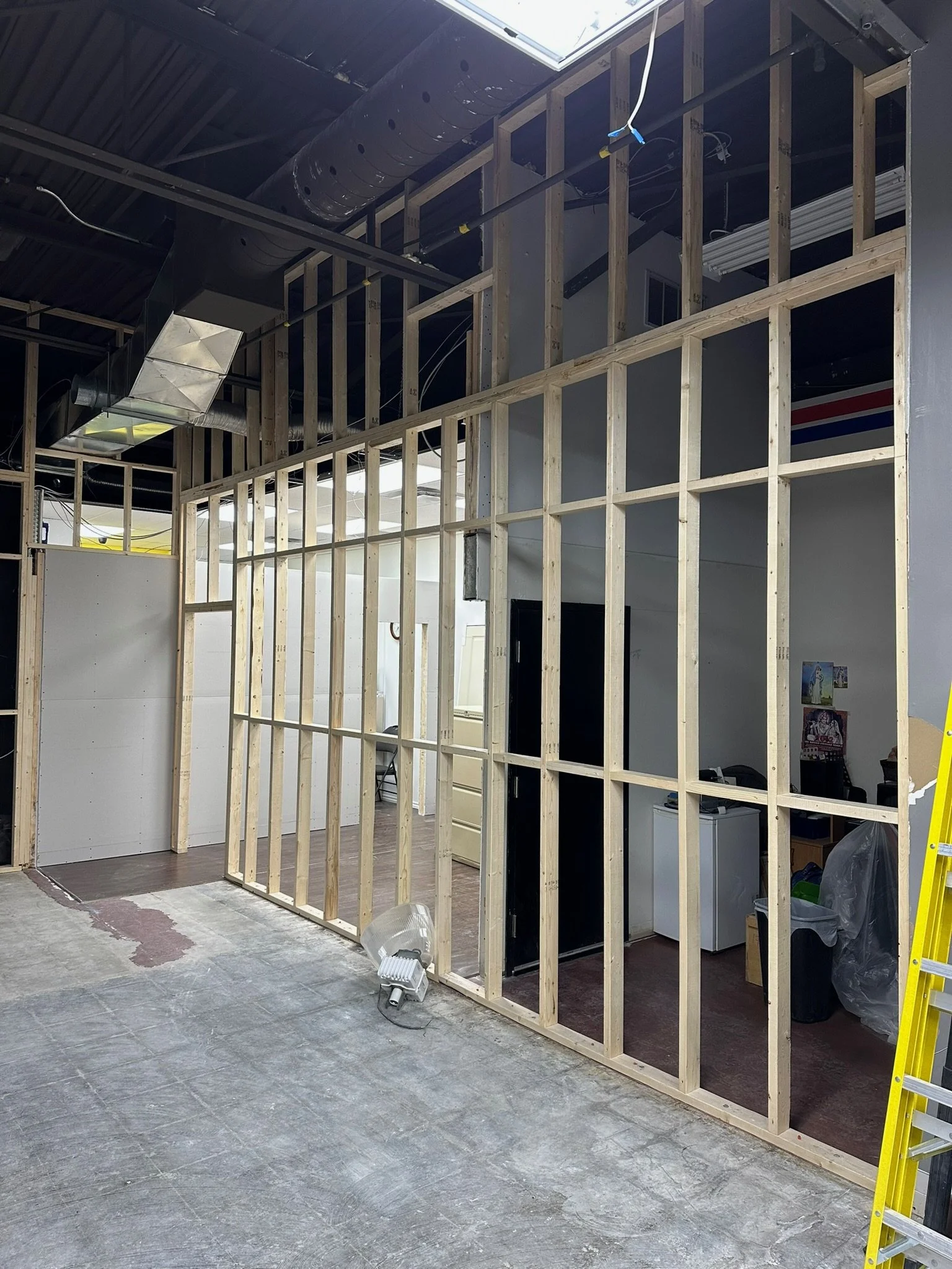 Construction site with wooden framing for a wall or partition inside a building, with some tools and construction materials on the floor.