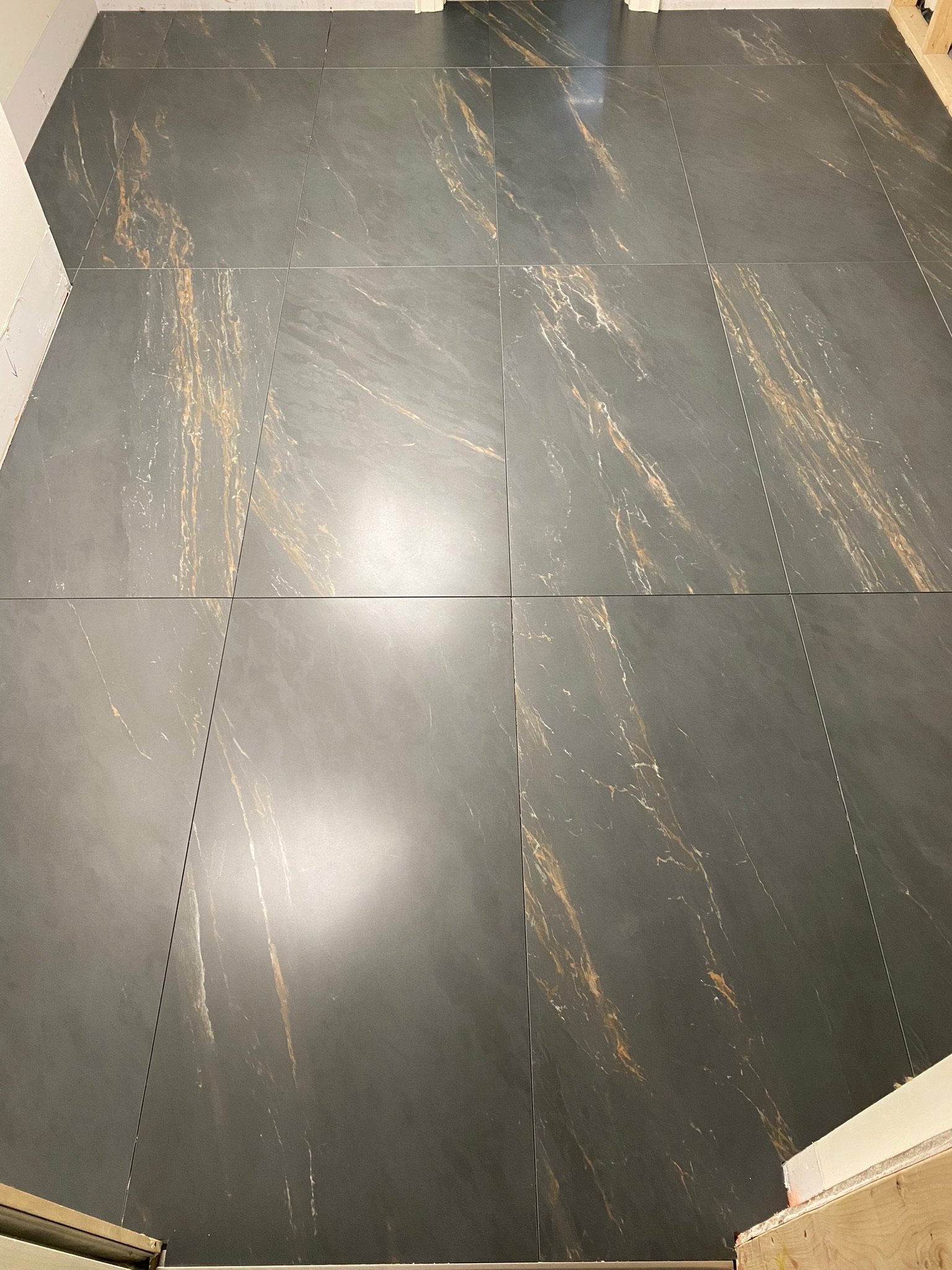 Photo of a dark gray tiled floor with gold and bronze veining.