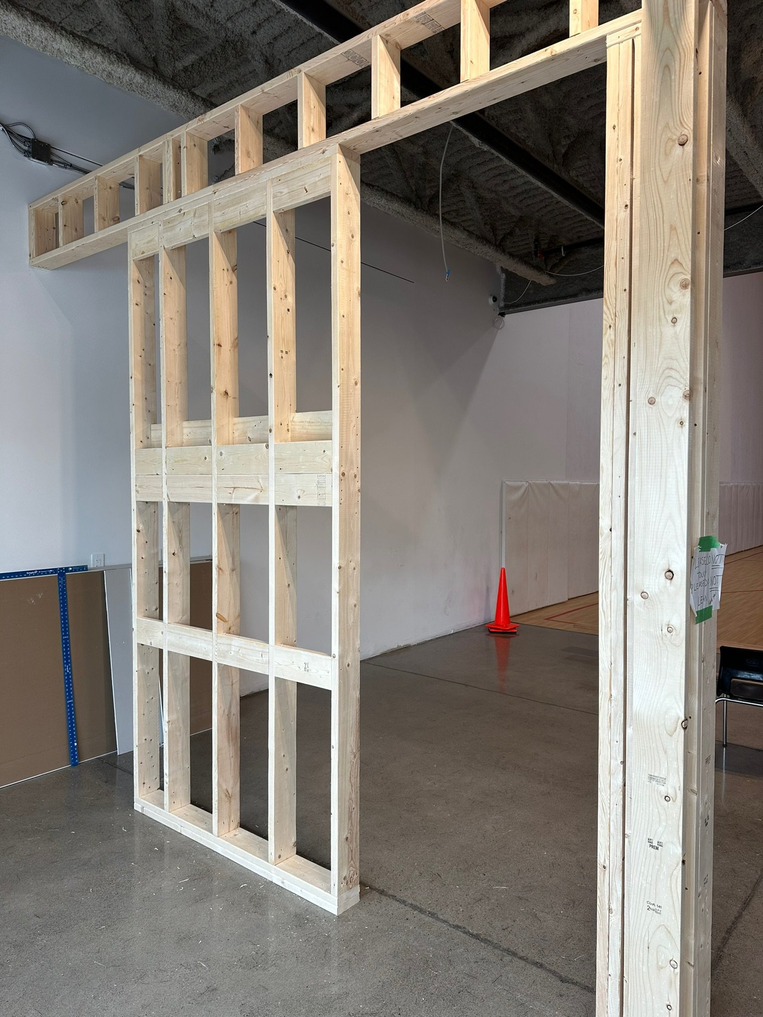 In-progress interior construction with a wooden framing structure, drywall leaning against the wall, and high-end construction tools.