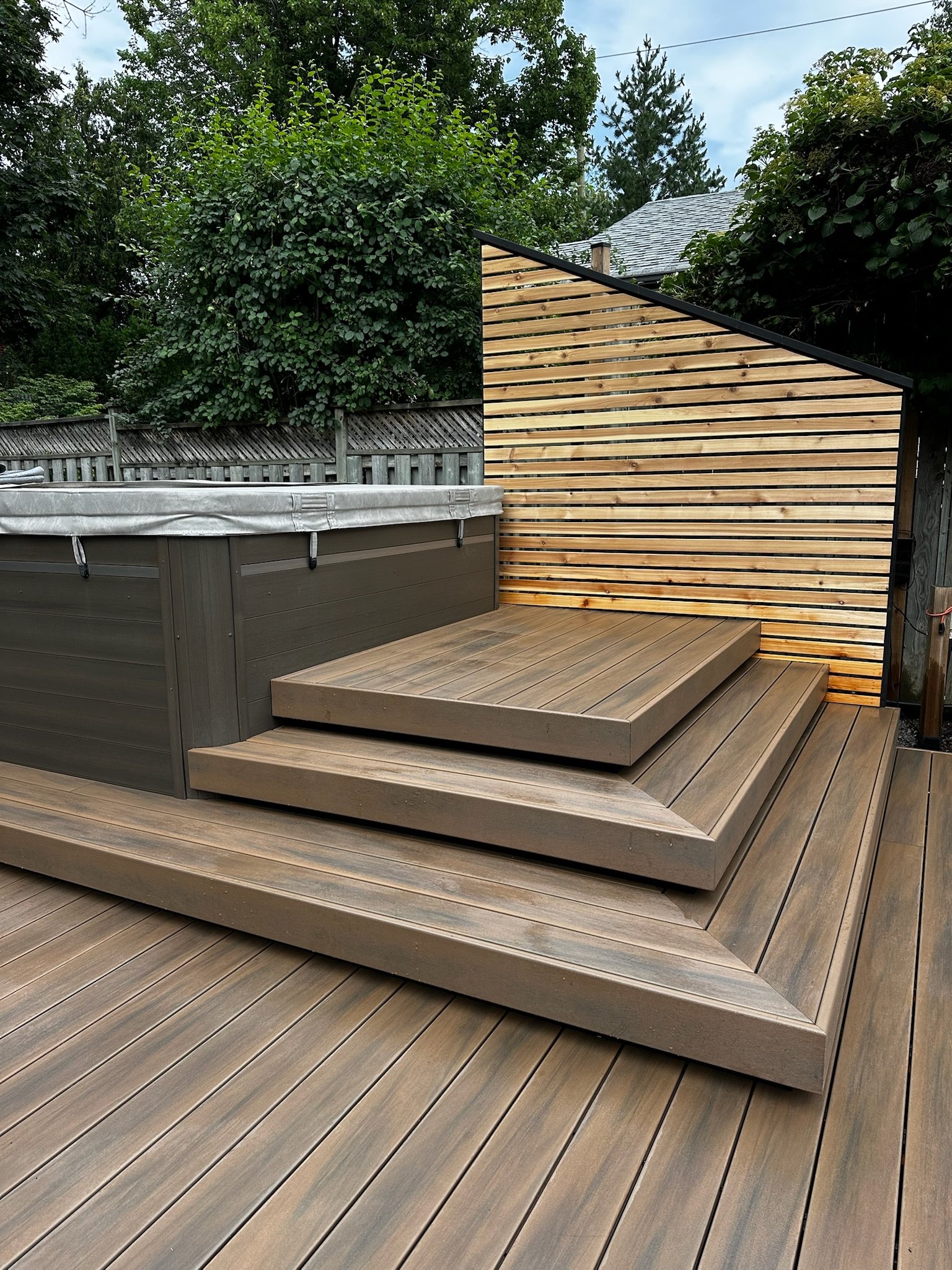 Deck with three tiered steps and bespoke built storage unit built around swim spa