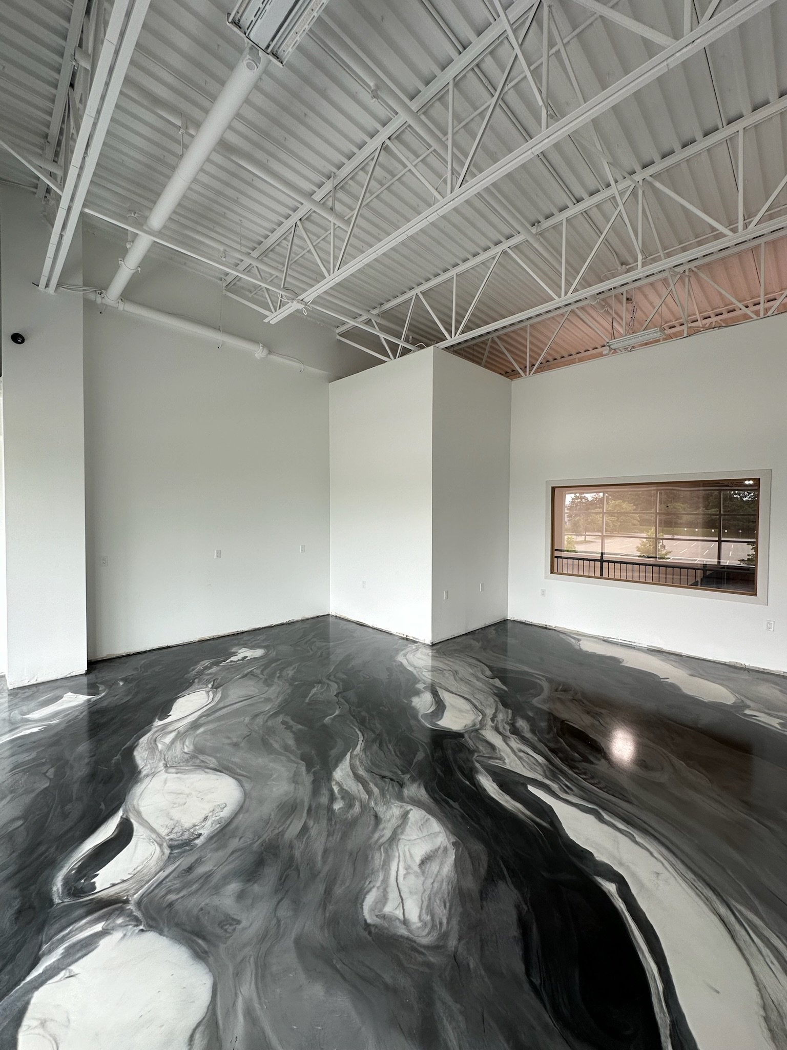 Interior of a modern building with white walls, large window, and a black and white marbled floor.