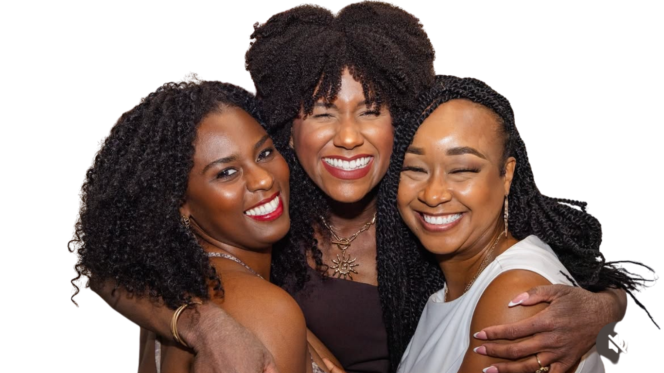 Three women hugging and smiling at the camera, showing their teeth, with joyful expressions.