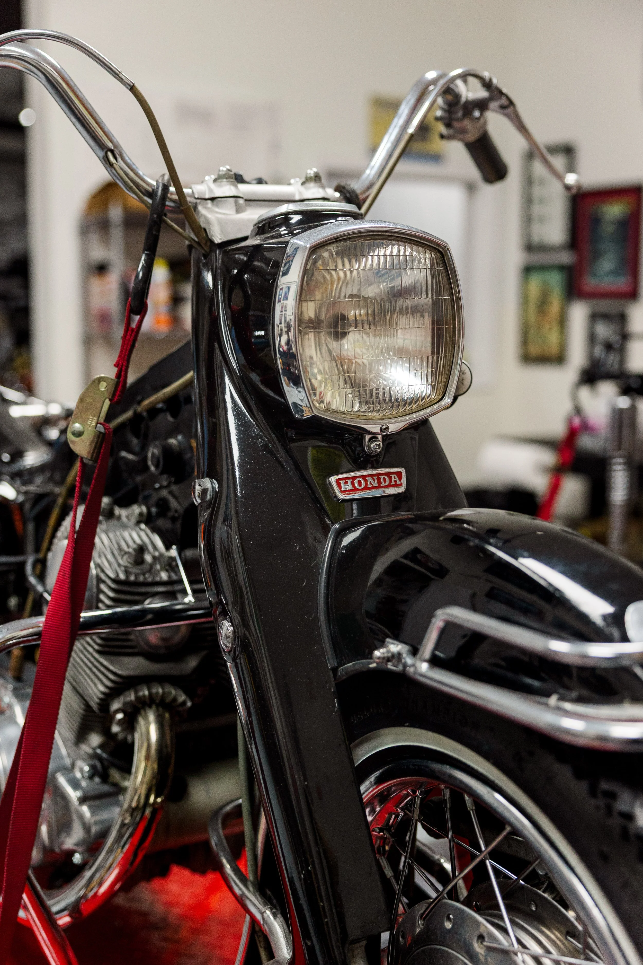 Close-up of a black Honda motorcycle front view in a garage, showing headlight, handlebars, and front wheel. Vintage motorcycle collection on display at Birmingham Vintage Cycle in Birmingham Alabama