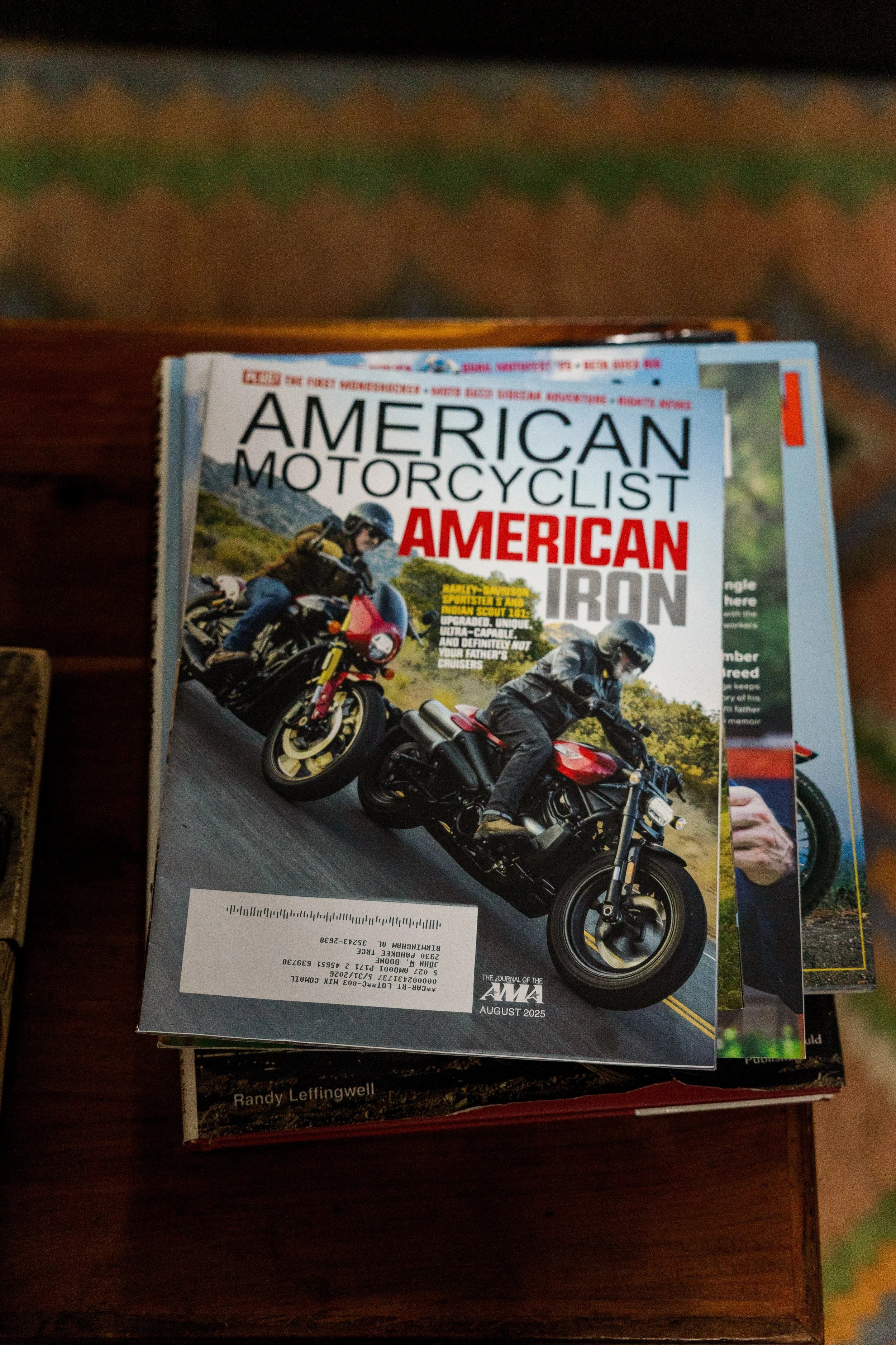 Magazine titled 'American Motorcylist' with a cover photo of two motorcyclists riding on a scenic road, dated August 2025. Inside Birmingham Vintage Cycle, a vintage motorcycle shop and community space in Birmingham Alabama