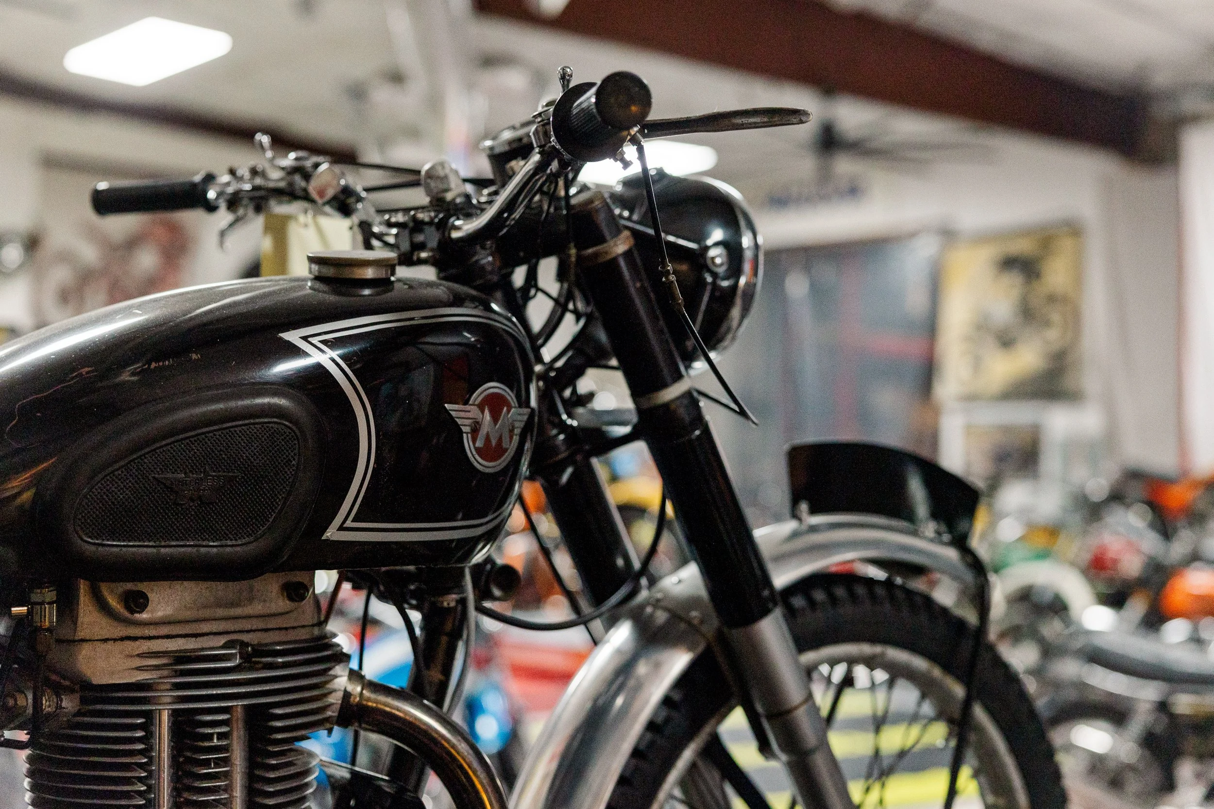 Close-up of a vintage motorcycle with black and chrome details, including the gas tank and engine, in a workshop setting. Vintage motorcycle detail at Birmingham Vintage Cycle, a vintage motorcycle restoration shop in Birmingham Alabama