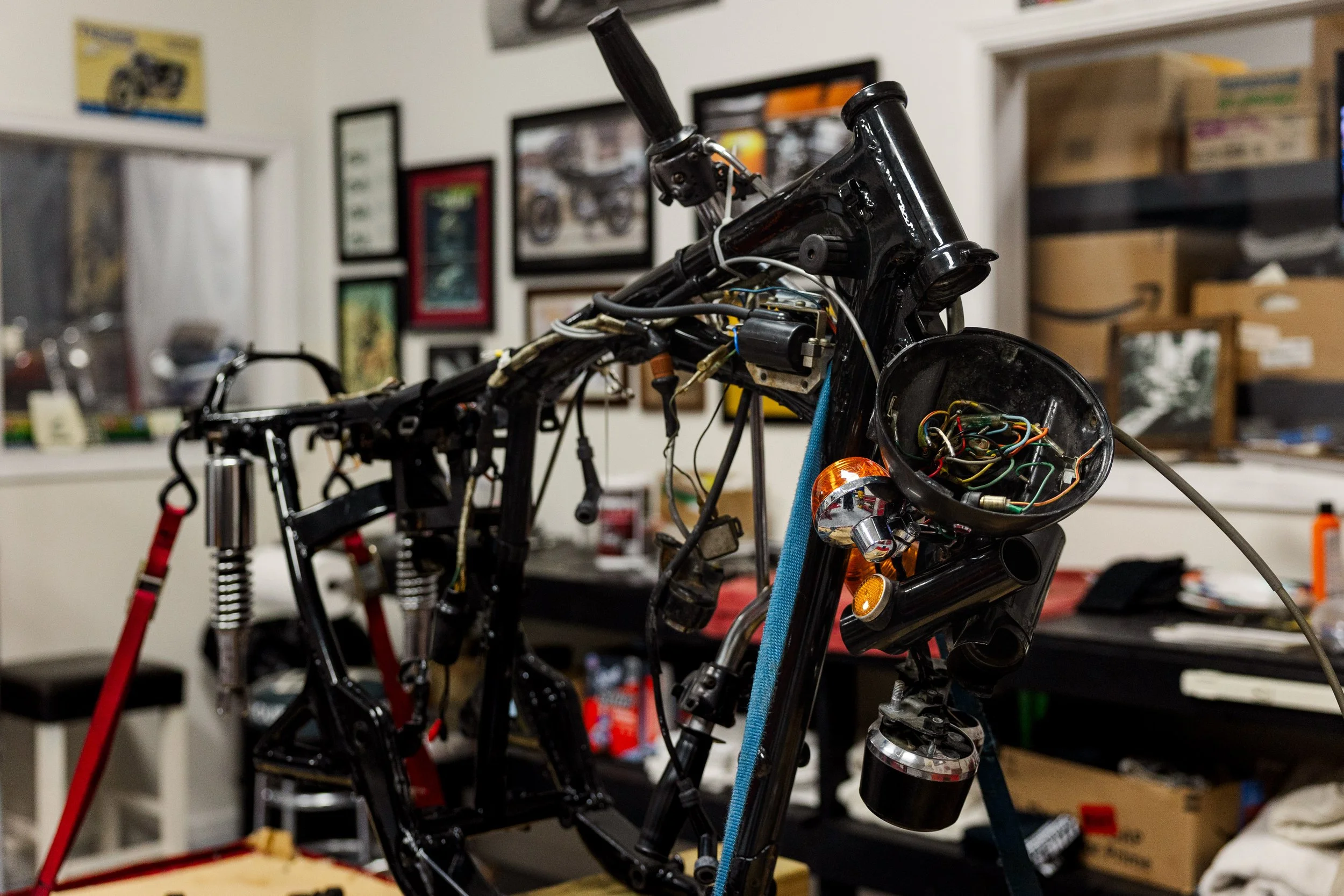 A partially assembled motorcycle with exposed wiring and components, on a workbench in a workshop. Vintage motorcycle collection on display at Birmingham Vintage Cycle in Birmingham Alabama