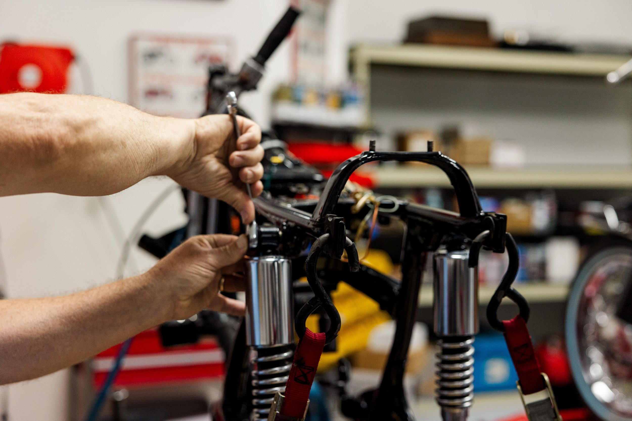 Person working on assembling or repairing the front suspension of a bike or motorcycle in a workshop. Vintage motorcycle detail at Birmingham Vintage Cycle, a vintage motorcycle restoration shop in Birmingham Alabama