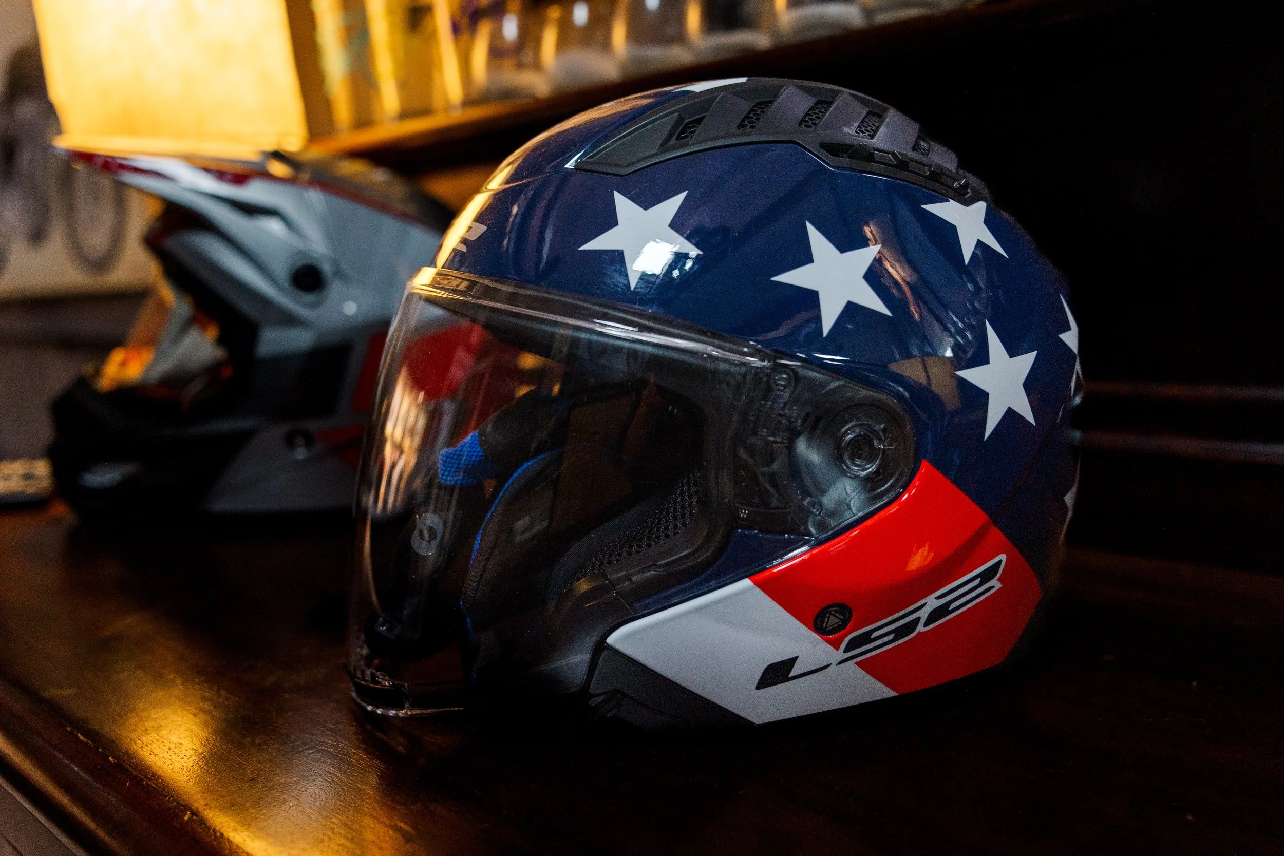 A motorcycle helmet with a star pattern on the blue top and a clear visor resting on a dark surface. Inside Birmingham Vintage Cycle, a vintage motorcycle shop and community space in Birmingham Alabama