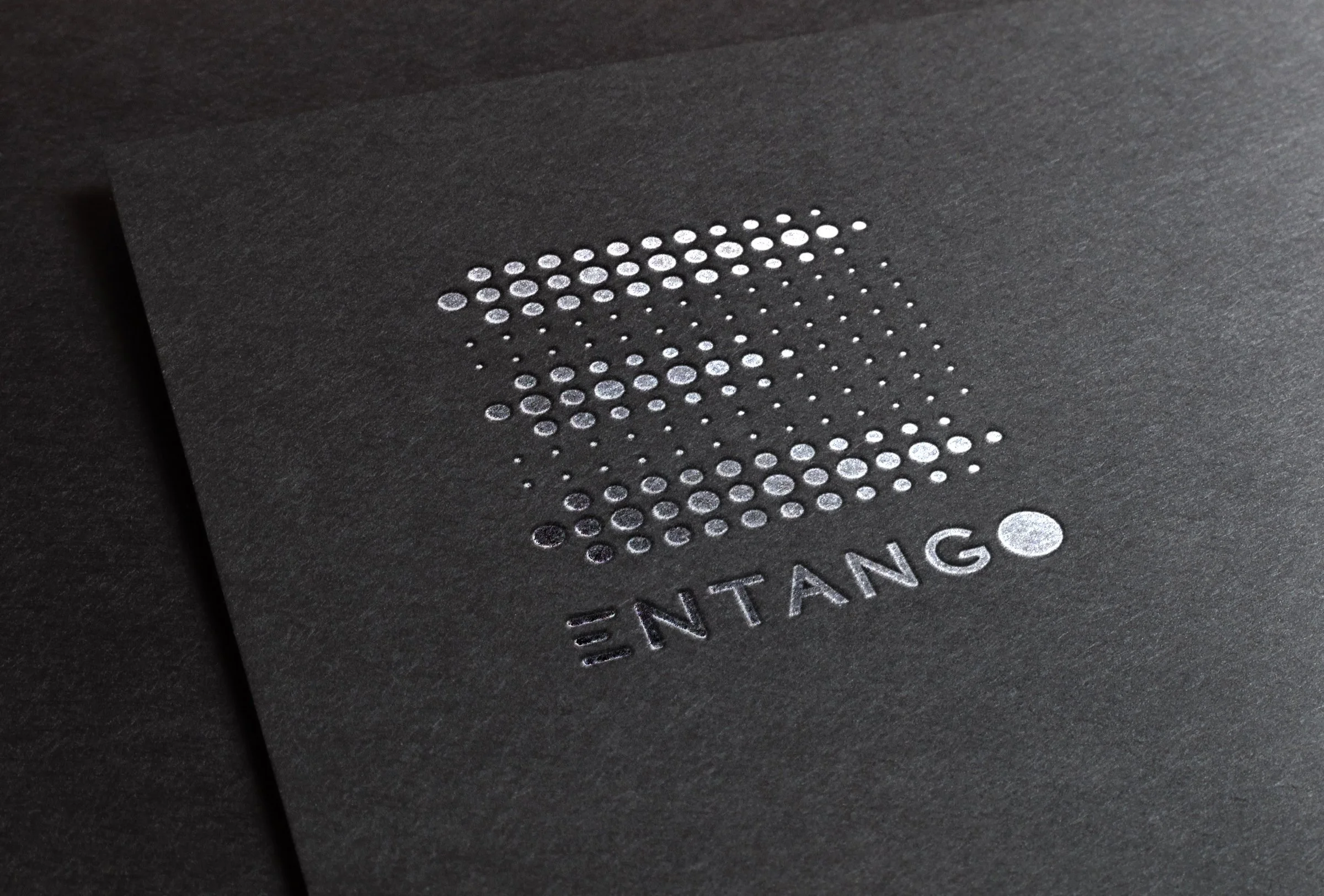 Close-up of a black surface with a pattern of white dots and the partial text 'ENTANG' visible.