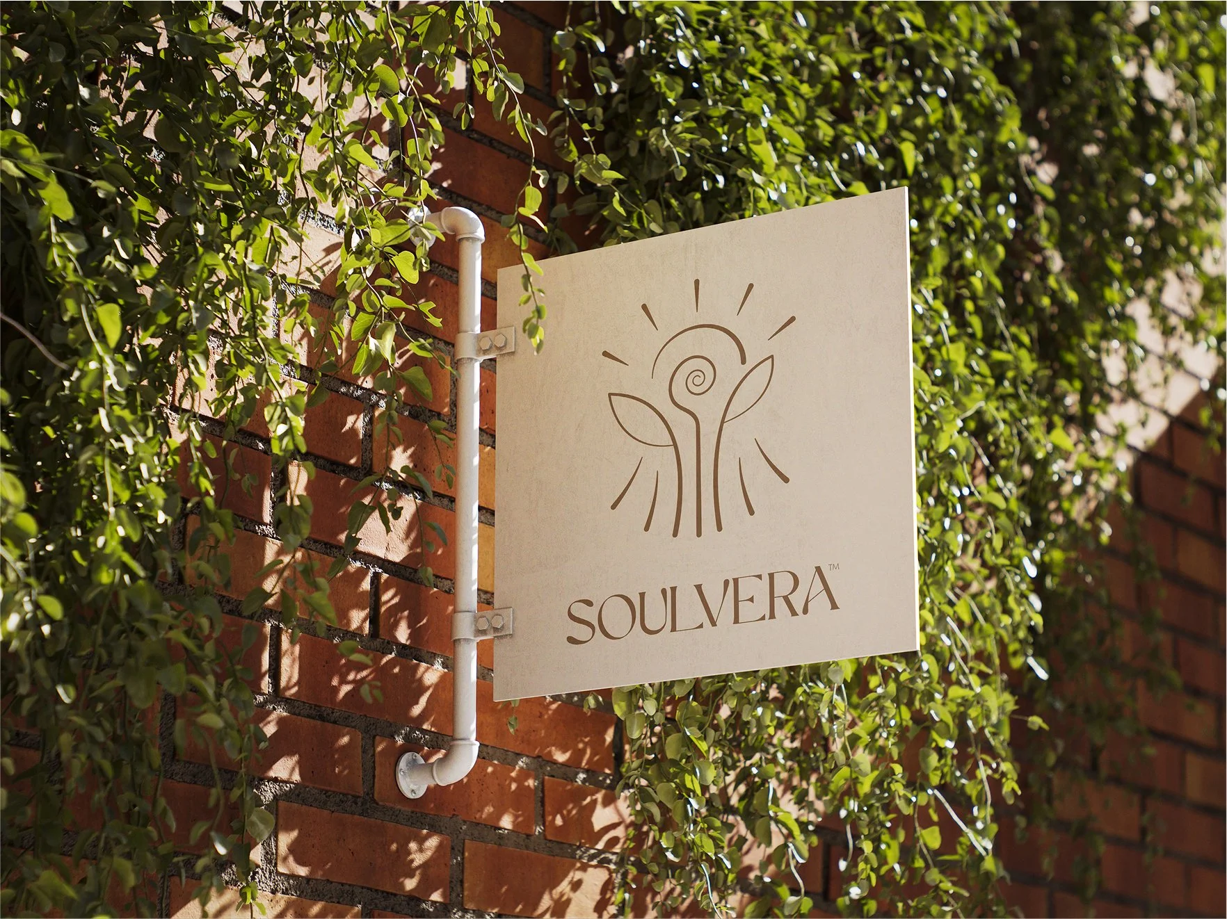A sign with the word "SOUVERA" and a logo of a stylized flower with leaves, mounted on a brick wall covered with green ivy.