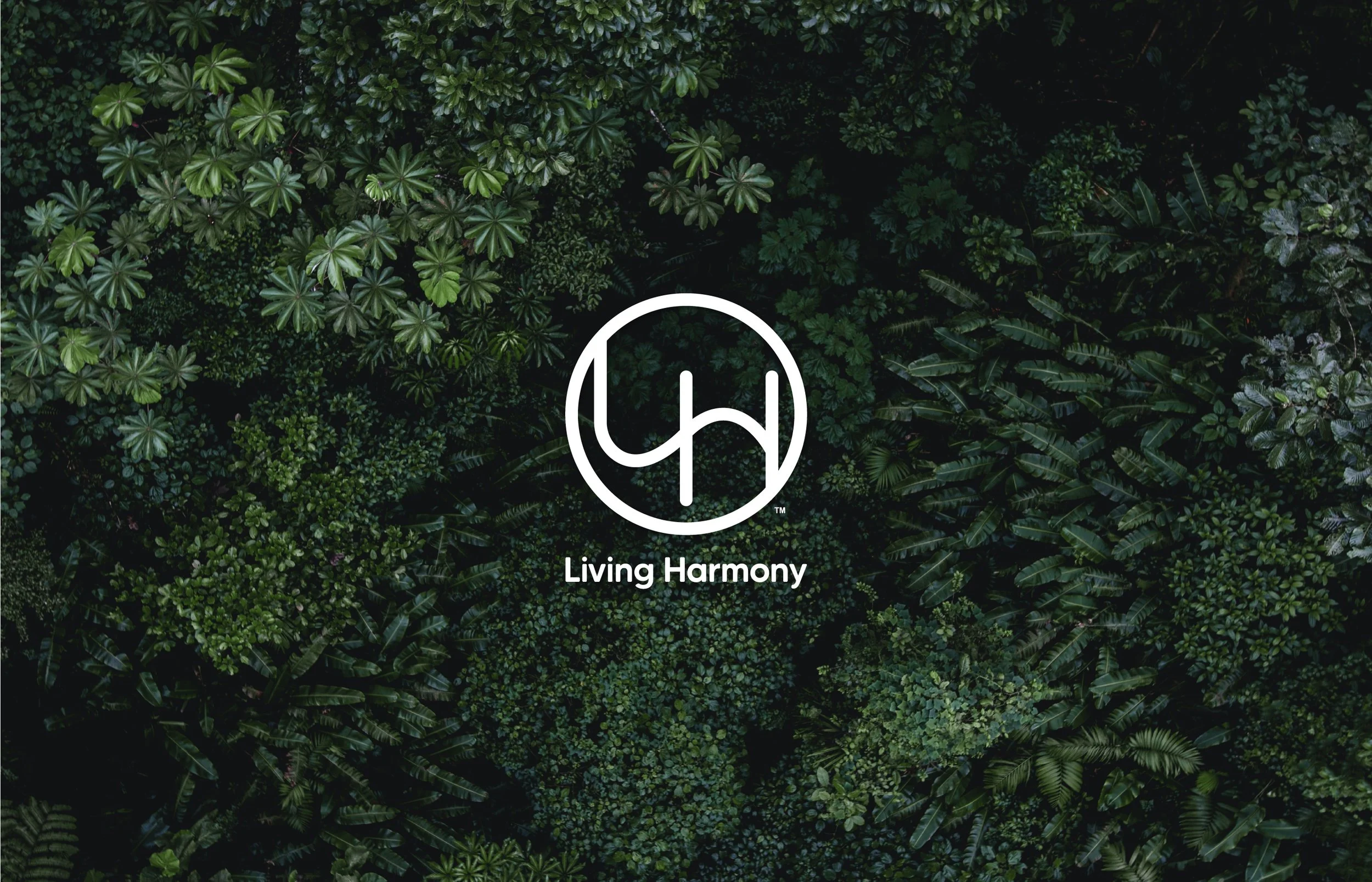 A top-down view of lush green tropical foliage with a white logo and the words 'Living Harmony' at the center.