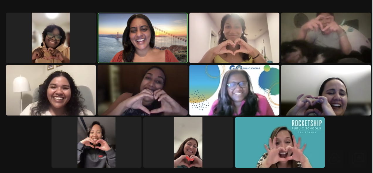 Screenshot of a virtual Zoom meeting with 12 participants, all smiling and making heart shapes with their hands. The background varies, including a bridge, logos, and indoor settings.