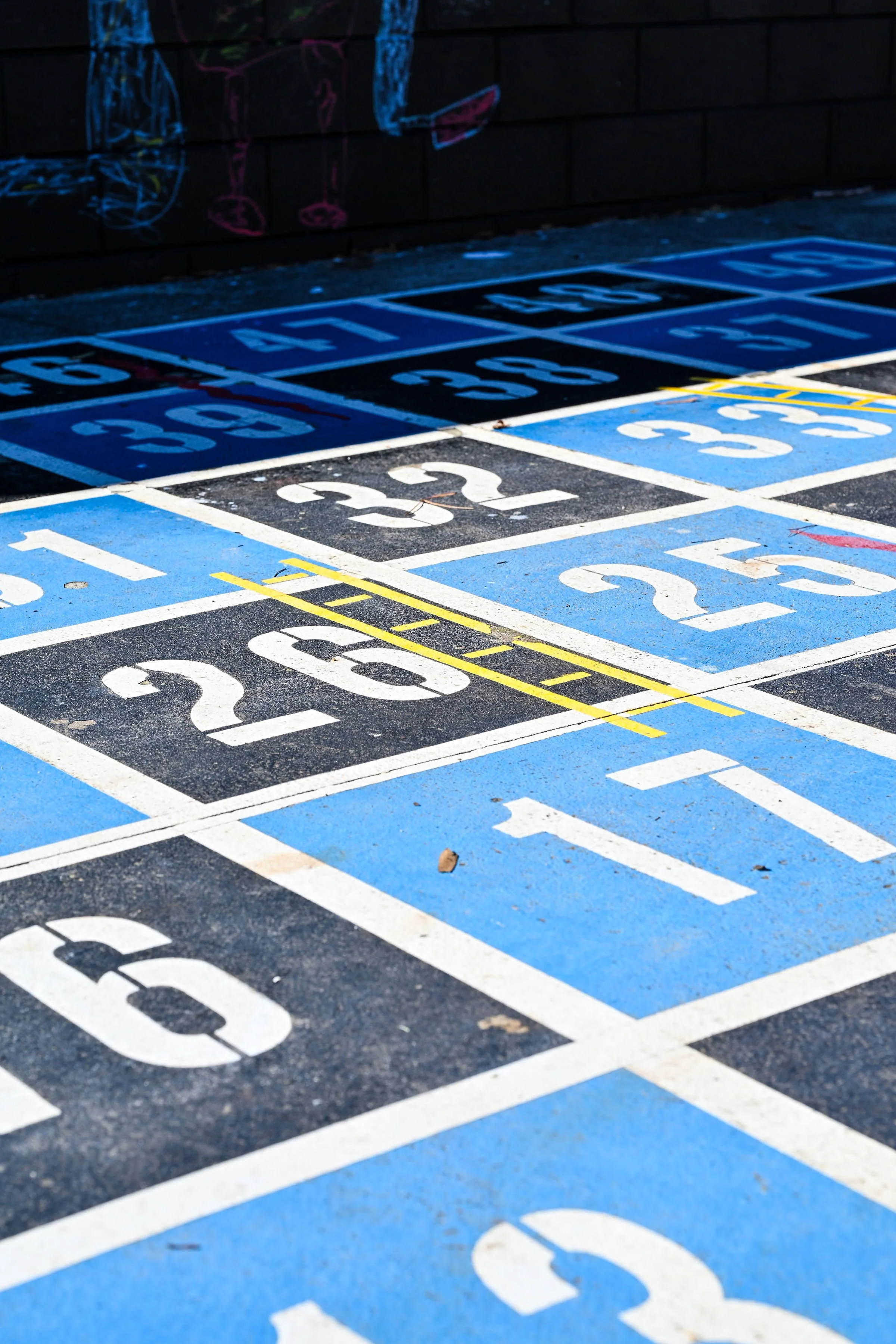 Colorful number game painted on pavement with navy and light blue squares with the numbers painted white.